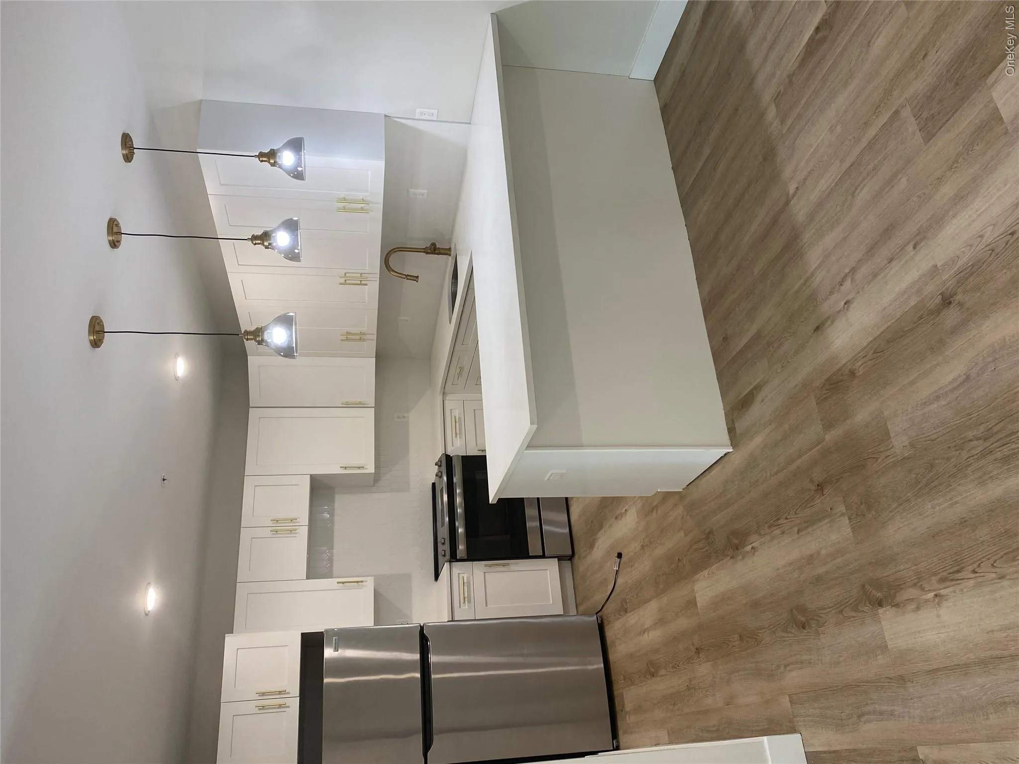 Contemporary kitchen featuring white cabinetry with brass hardware, a stainless steel appliance suite, and light-toned countertops Contemporary kitchen featuring white cabinetry with brass hardware, a stainless steel appliance suite, and light-toned countertops