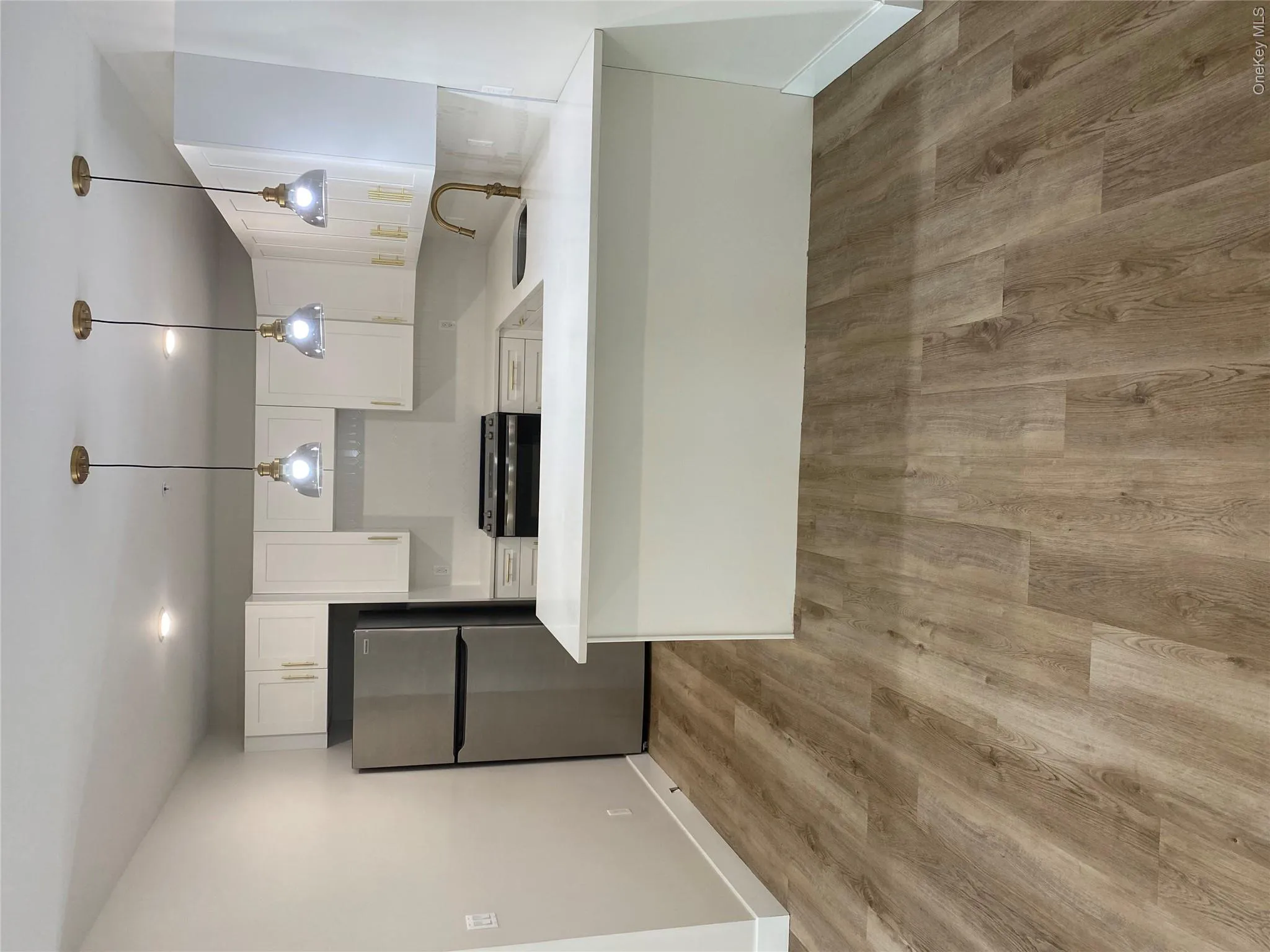 Modern kitchen featuring white cabinetry with gold-tone hardware, stainless steel appliances, quartz countertops and a U-shaped countertop Modern kitchen featuring white cabinetry with gold-tone hardware, stainless steel appliances, quartz countertops and a U-shaped countertop