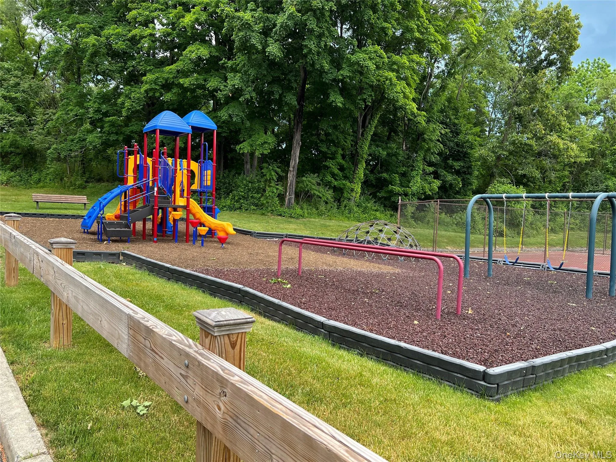 Community playground featuring a colorful playset with slides, swings, and climbing dome Community playground featuring a colorful playset with slides, swings, and climbing dome