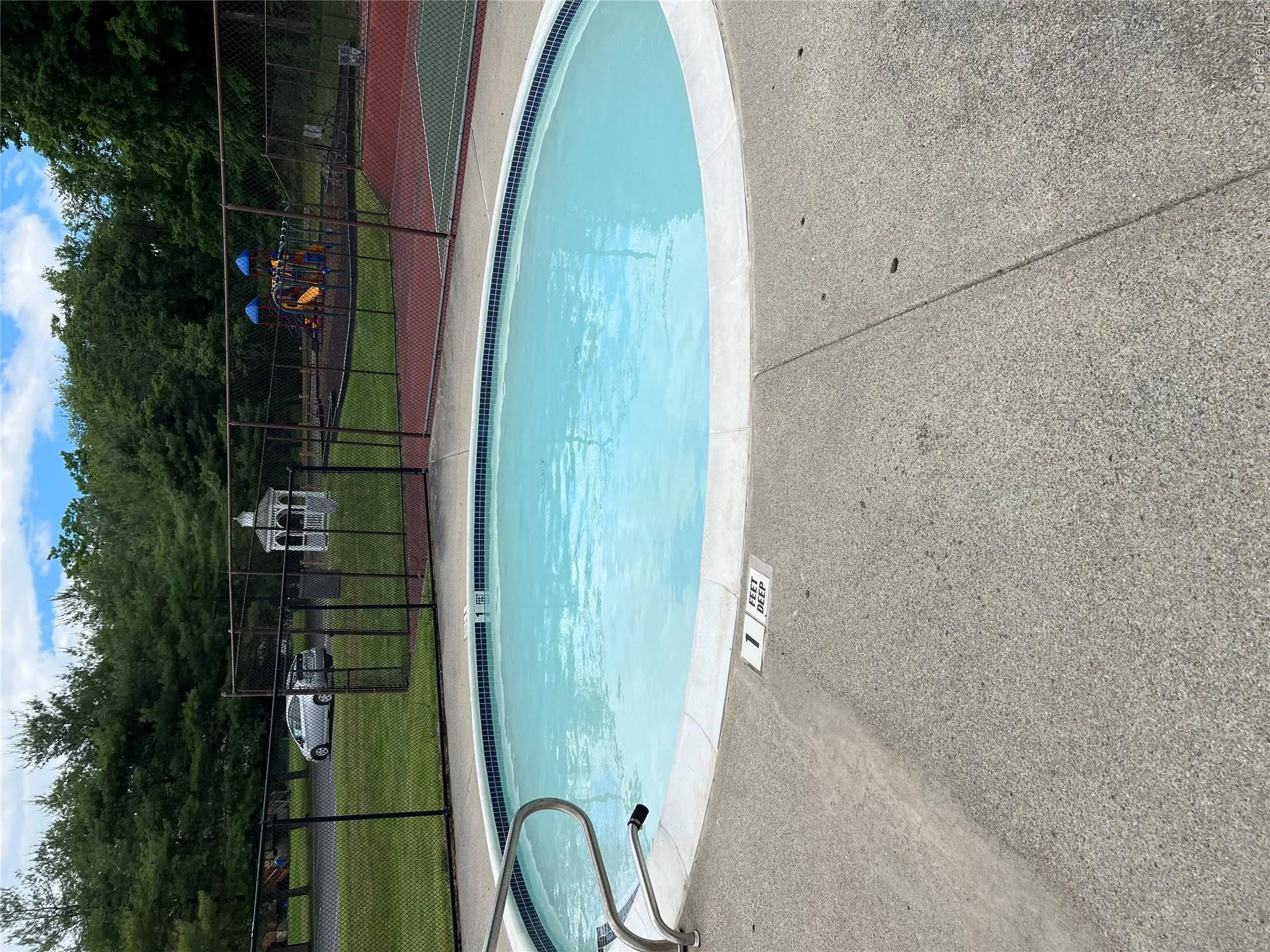 Oval pool featuring a blue tile waterline and surrounding concrete decking Oval pool featuring a blue tile waterline and surrounding concrete decking