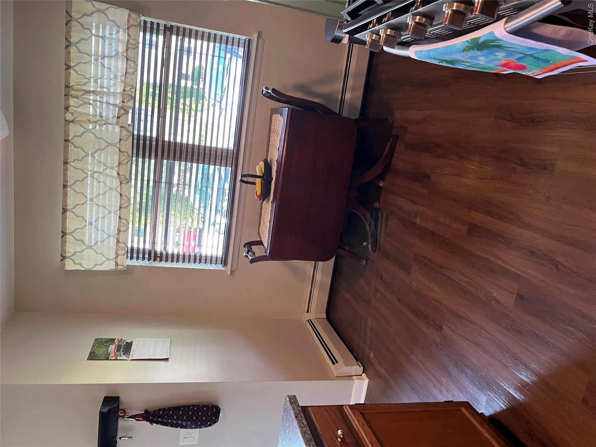 Wood-finish flooring paired with light beige walls and a window featuring horizontal blinds Wood-finish flooring paired with light beige walls and a window featuring horizontal blinds