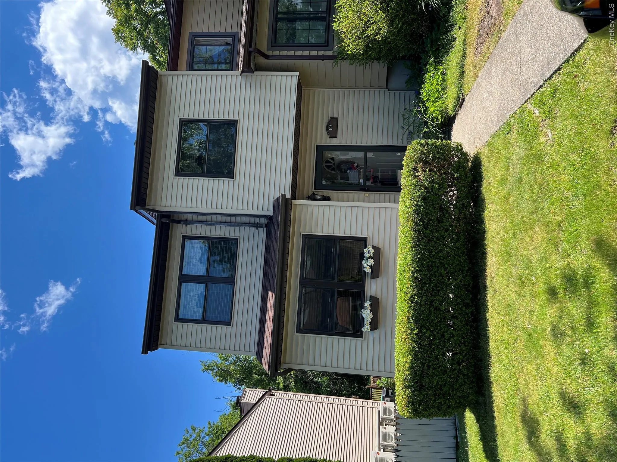 Two-story townhouse exterior featuring tan siding and dark trim Two-story townhouse exterior featuring tan siding and dark trim