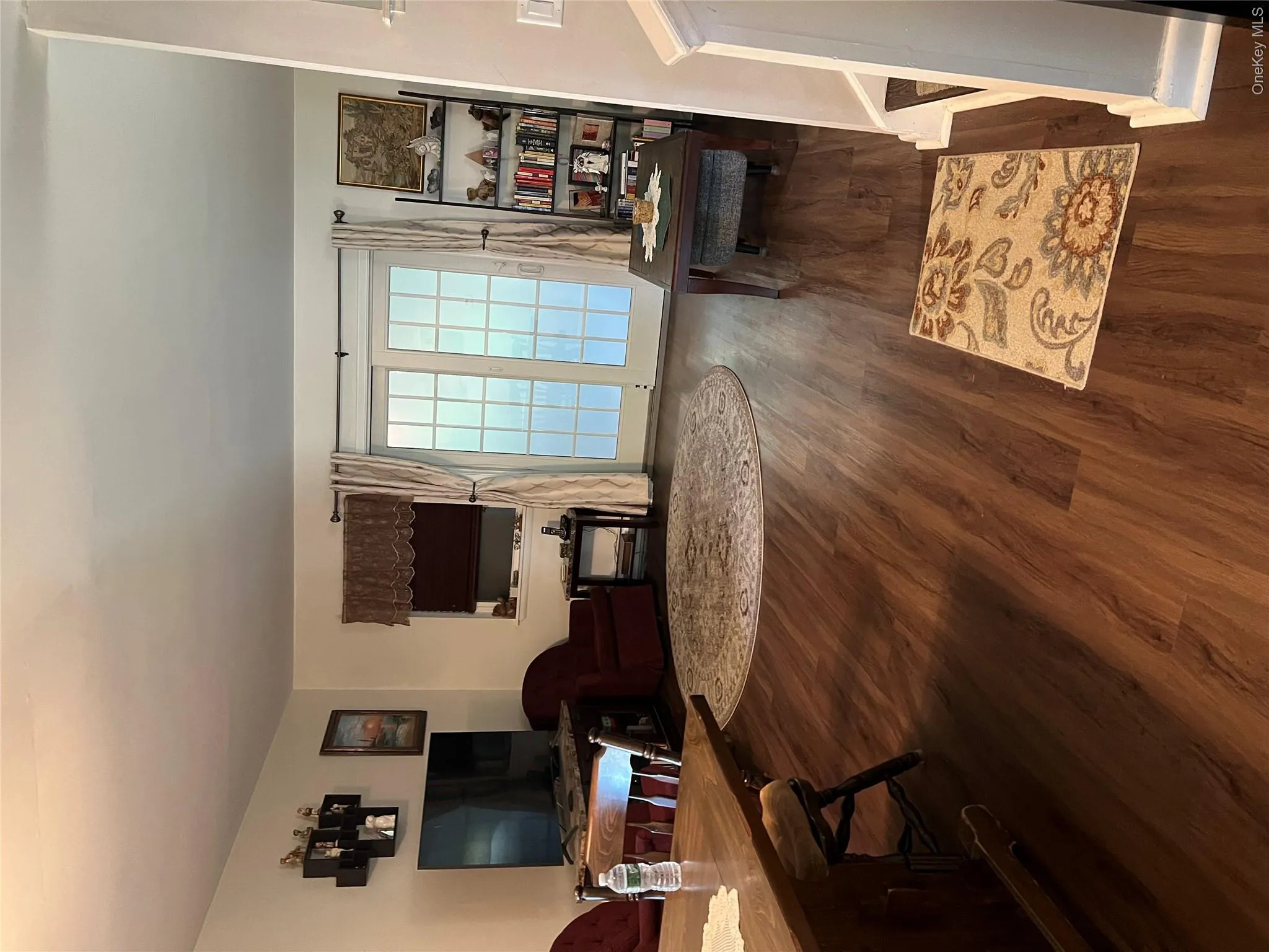 Spacious living area featuring wood-finish flooring, white walls, and bright sliding glass doors Spacious living area featuring wood-finish flooring, white walls, and bright sliding glass doors