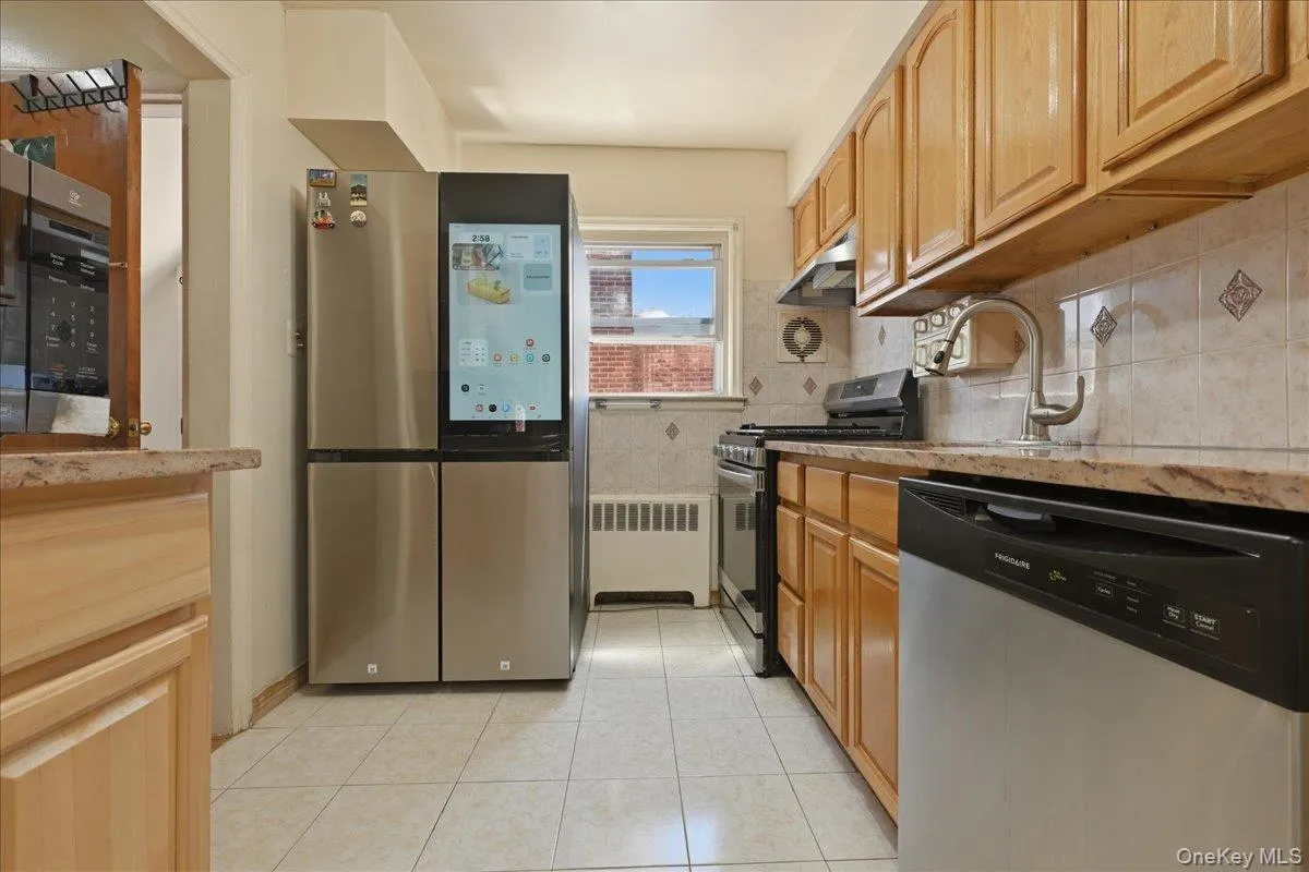 Efficient kitchen featuring a stainless steel refrigerator with an integrated display, wood-finish cabinetry, a gas range, and a stainless steel dishwasher Efficient kitchen featuring a stainless steel refrigerator with an integrated display, wood-finish cabinetry, a gas range, and a stainless steel dishwasher