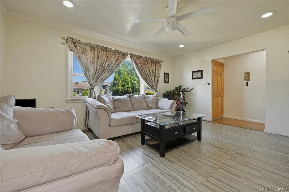 Brightly lit interior space featuring wood-finish flooring, a contemporary ceiling fan, recessed lighting, and crown molding Brightly lit interior space featuring wood-finish flooring, a contemporary ceiling fan, recessed lighting, and crown molding