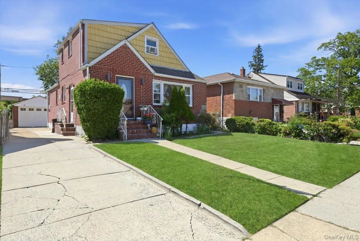 Brick and siding exterior residence featuring a front lawn and a long concrete driveway leading to a detached garage Brick and siding exterior residence featuring a front lawn and a long concrete driveway leading to a detached garage