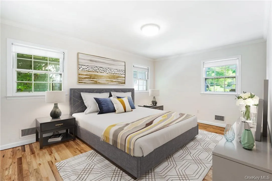 Bedroom featuring crown molding, light hardwood / wood-style flooring, and multiple windows Bedroom featuring crown molding, light hardwood / wood-style flooring, and multiple windows