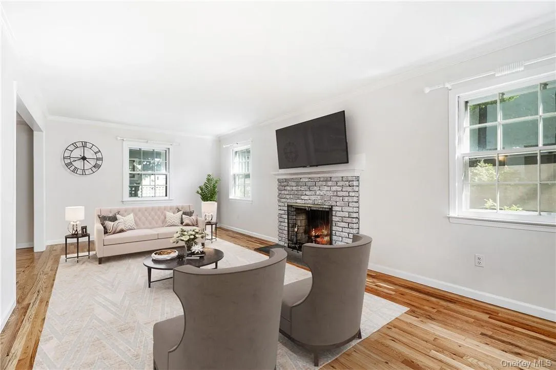 Living room featuring ornamental molding, light hardwood / wood-style flooring, and a brick fireplace Living room featuring ornamental molding, light hardwood / wood-style flooring, and a brick fireplace