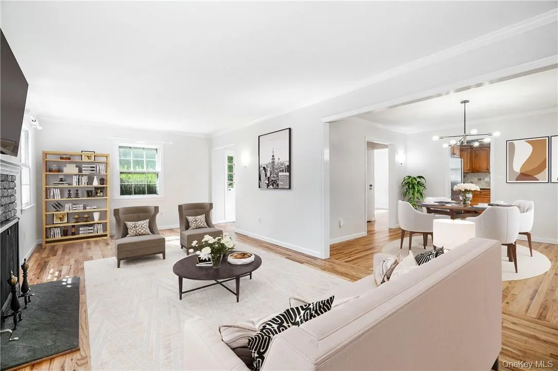 Living room with a stone fireplace, wood-type flooring, a notable chandelier, and crown molding Living room with a stone fireplace, wood-type flooring, a notable chandelier, and crown molding