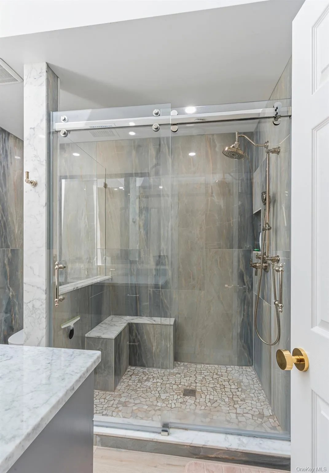 The Magnificent Primary Bathroom Has Been Gutted Down To The Studs & Offers A Spectacular Oversized Custom Shower With All 24" x 48" Stone Tiled Walls, Built In L Shaped Bench, Pebble Stone Style Floor, Wheeled/Rolling Frameless Glass Doors & High End Shower Fittings. The Magnificent Primary Bathroom Has Been Gutted Down To The Studs & Offers A Spectacular Oversized Custom Shower With All 24" x 48" Stone Tiled Walls, Built In L Shaped Bench, Pebble Stone Style Floor, Wheeled/Rolling Frameless Glass Doors & High End Shower Fittings.