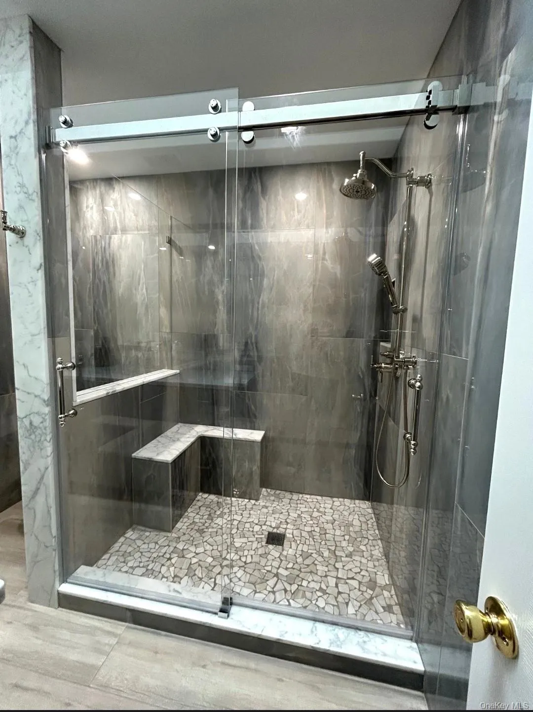 The Magnificent Primary Bathroom Has Been Gutted Down To The Studs & Offers A Spectacular Oversized Custom Shower With All 24" x 48" Stone Tiled Walls, Built In L Shaped Bench, Pebble Stone Style Floor, Wheeled/Rolling Frameless Glass Doors & High End Shower Fittings. The Magnificent Primary Bathroom Has Been Gutted Down To The Studs & Offers A Spectacular Oversized Custom Shower With All 24" x 48" Stone Tiled Walls, Built In L Shaped Bench, Pebble Stone Style Floor, Wheeled/Rolling Frameless Glass Doors & High End Shower Fittings.