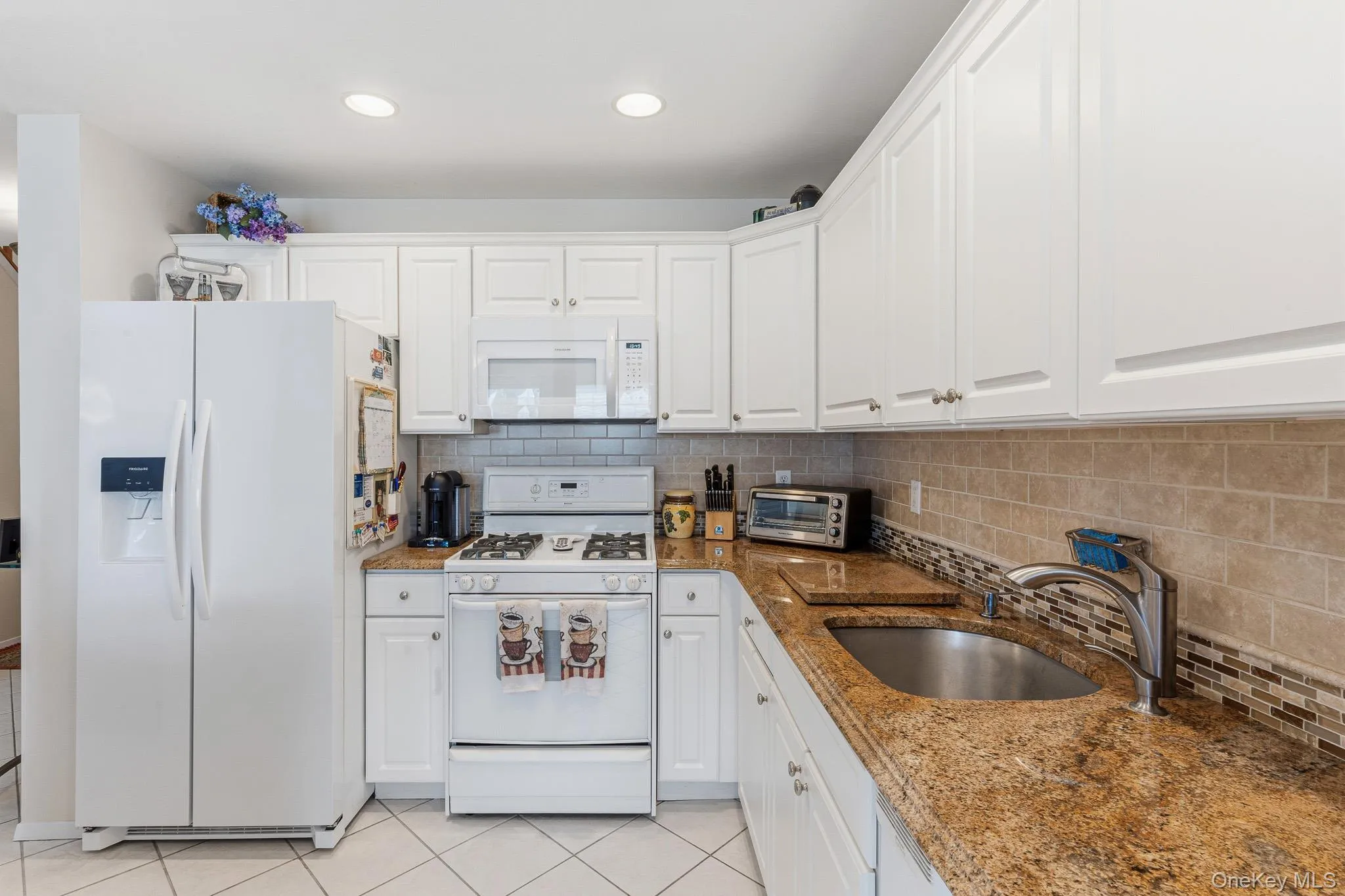 The Beautifully Upgraded Eat In Kitchen Offers Walls Of White Raised Panel Cabinetry, Beautiful Crown Moldings, Bullnose Edged Granite Countertops With An Undermount Sink, Accent Tiled Backsplash With Both Ceramic Tile & Glass/Mosaic Tile, Frigidaire Gas Stove, Built In Microwave Oven, Two Year Old Frigidaire Side By Side Refrigerator With Water & ice Maker, Frigidaire Dishwasher, Large Built In Pantry, Recessed Lighting, Diagonal Ceramic Tile Floors, And The Kitchen Opens Into The Great Room. The Beautifully Upgraded Eat In Kitchen Offers Walls Of White Raised Panel Cabinetry, Beautiful Crown Moldings, Bullnose Edged Granite Countertops With An Undermount Sink, Accent Tiled Backsplash With Both Ceramic Tile & Glass/Mosaic Tile, Frigidaire Gas Stove, Built In Microwave Oven, Two Year Old Frigidaire Side By Side Refrigerator With Water & ice Maker, Frigidaire Dishwasher, Large Built In Pantry, Recessed Lighting, Diagonal Ceramic Tile Floors, And The Kitchen Opens Into The Great Room.