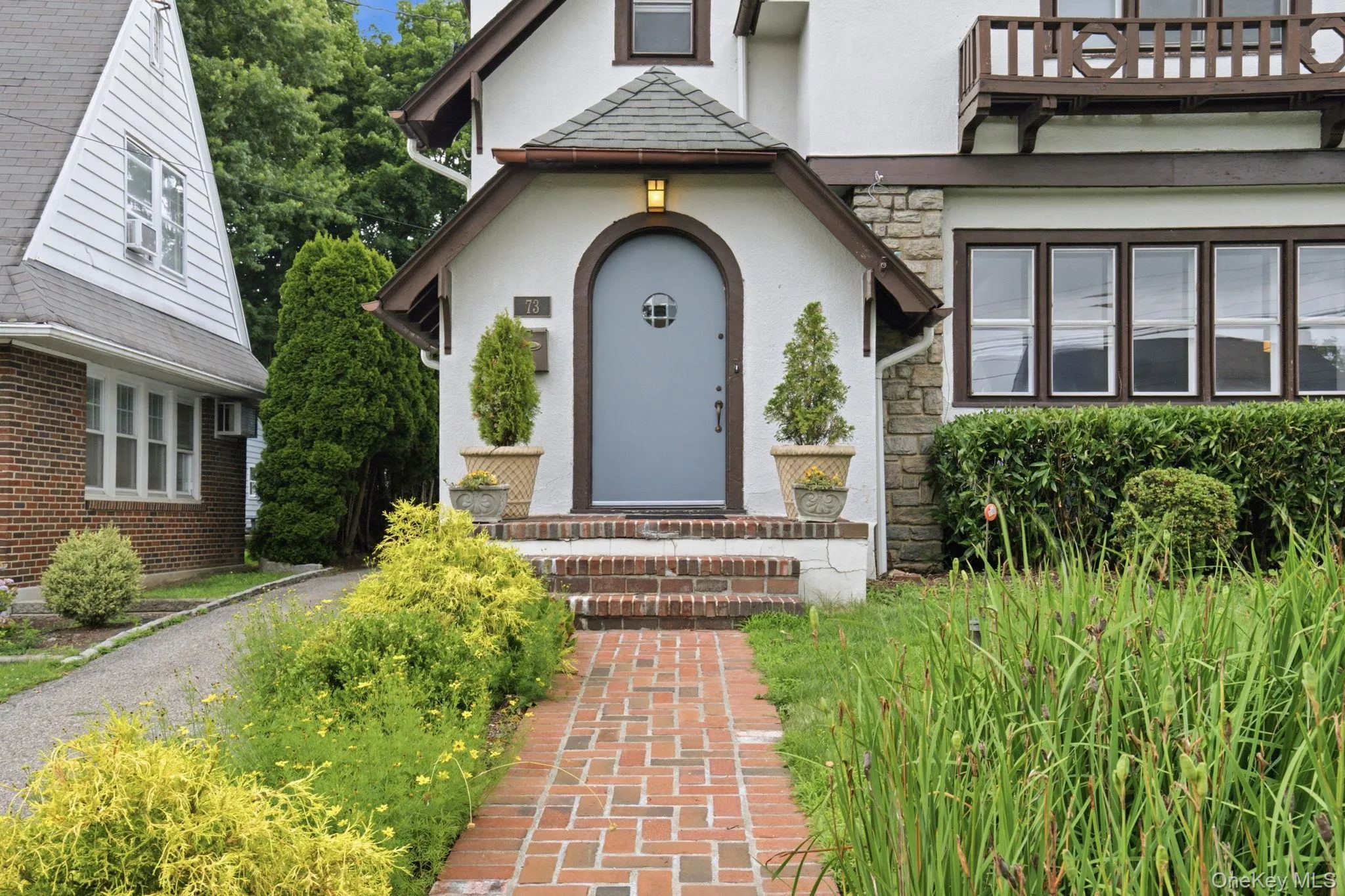 A brick walkway leads to the arched front entry beneath its own peaked portico. A brick walkway leads to the arched front entry beneath its own peaked portico.