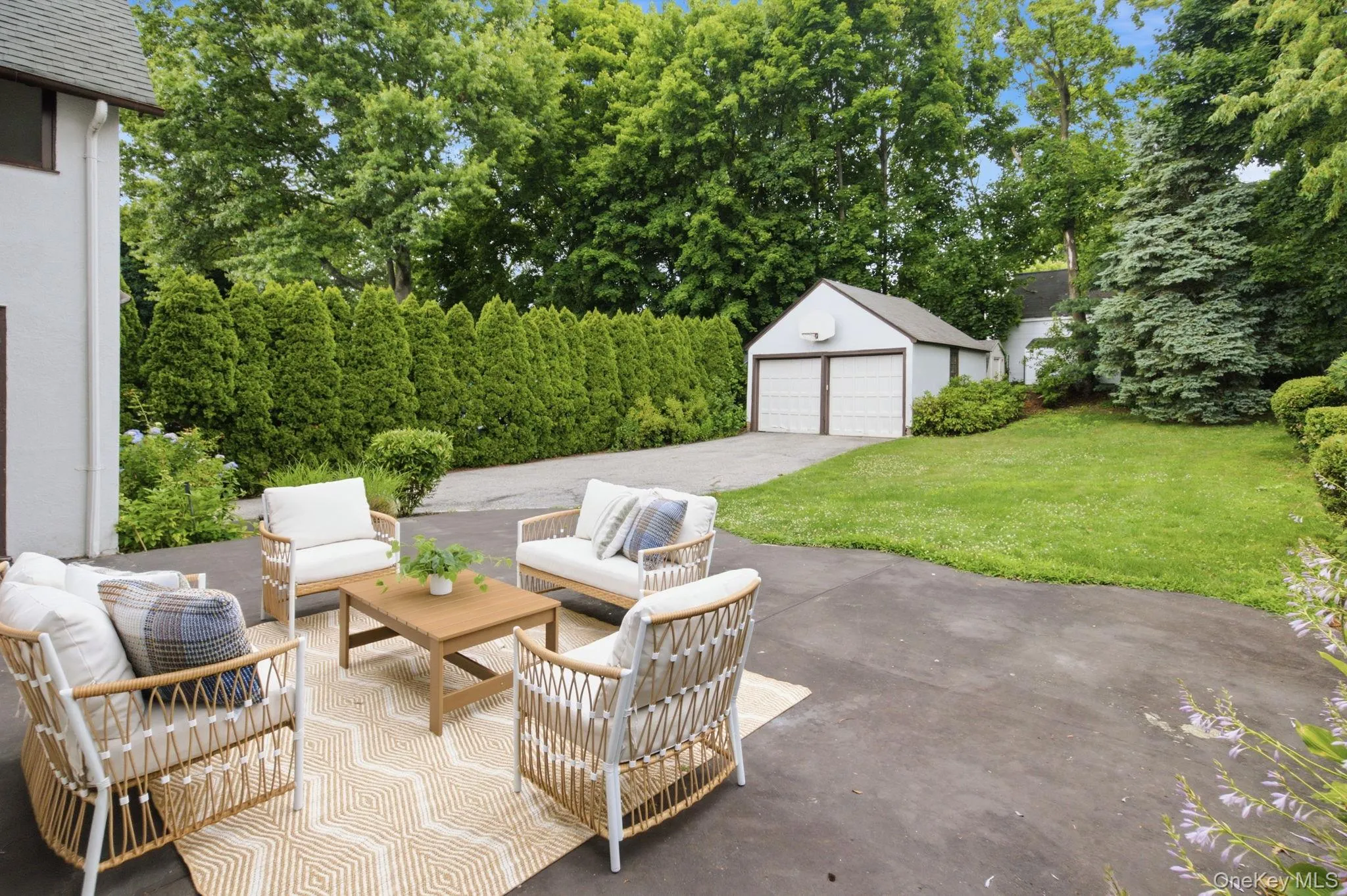 A generous patio extends the living space outdoors, framed by lawn and evergreens. A generous patio extends the living space outdoors, framed by lawn and evergreens.