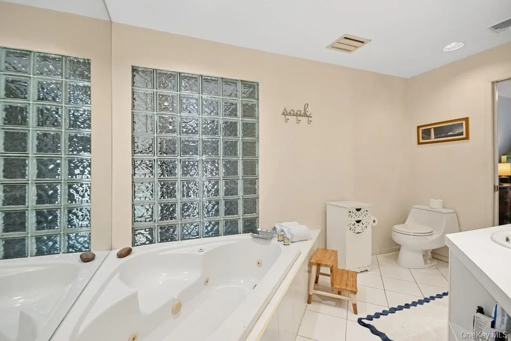 Soaking tub with jetted features, framed by a glass block wall, spa shower Soaking tub with jetted features, framed by a glass block wall, spa shower