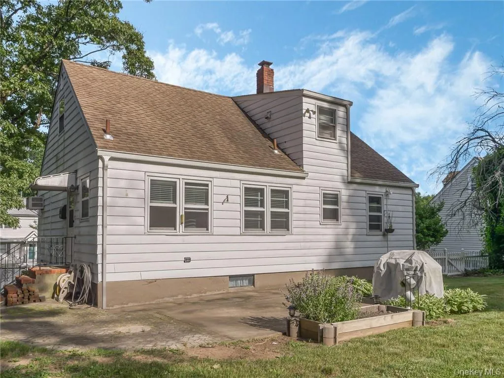 Rear view of house with a patio area, a lawn, and a wall mounted air conditioner Rear view of house with a patio area, a lawn, and a wall mounted air conditioner