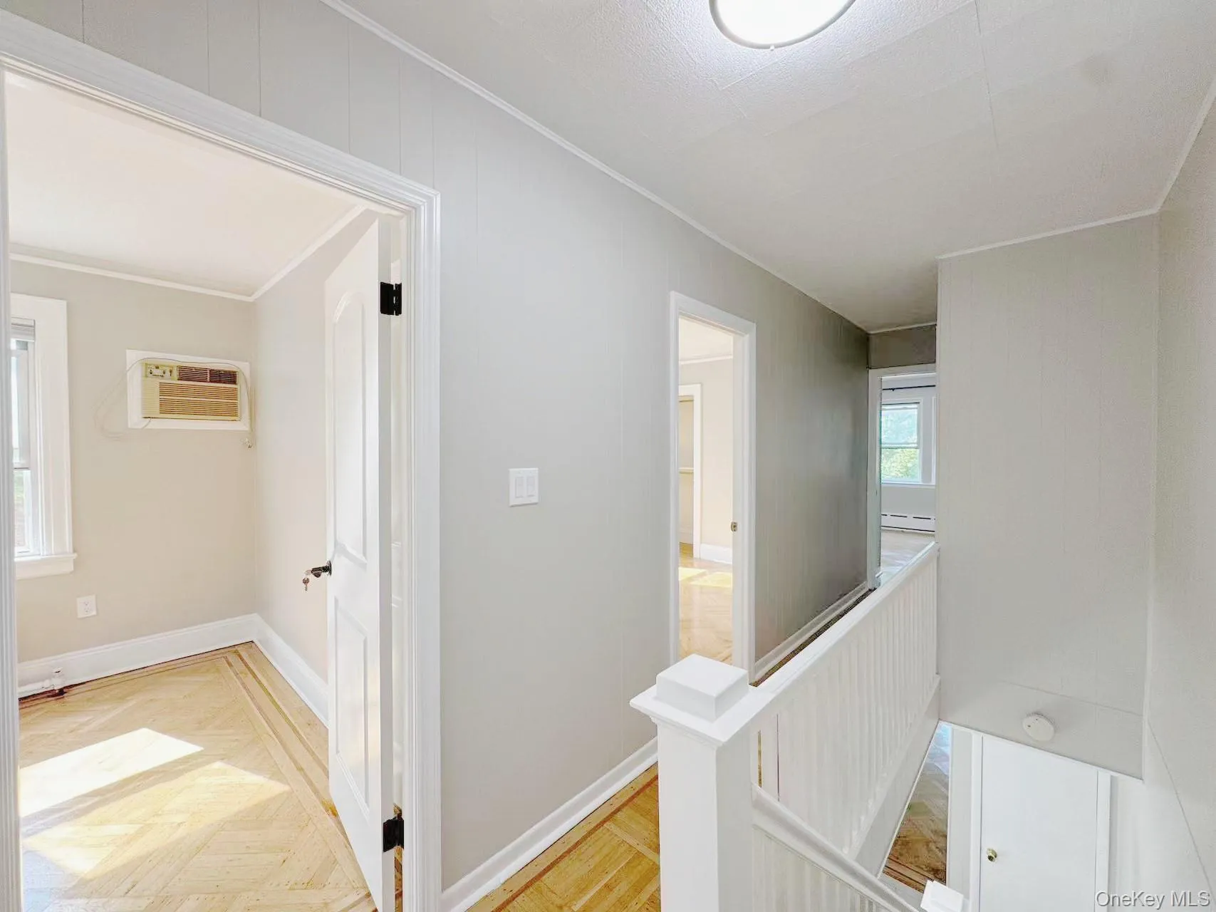 Upper-level hallway with light-toned wall finishes, white trim, and a white balustrade Upper-level hallway with light-toned wall finishes, white trim, and a white balustrade