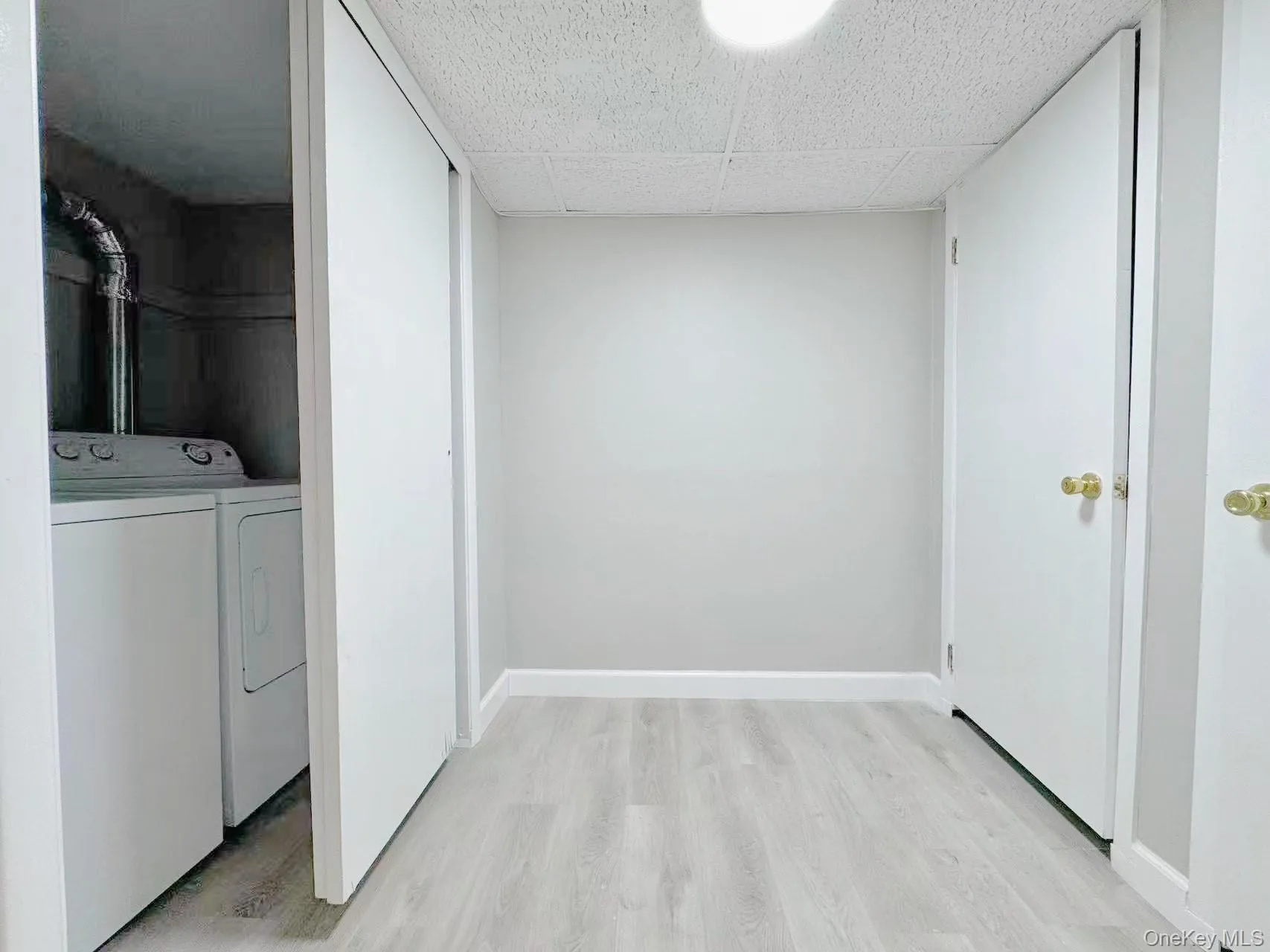 Dedicated laundry area with a white washer and dryer, complemented by light wood-finish flooring, white baseboards, and a neutral wall color Dedicated laundry area with a white washer and dryer, complemented by light wood-finish flooring, white baseboards, and a neutral wall color