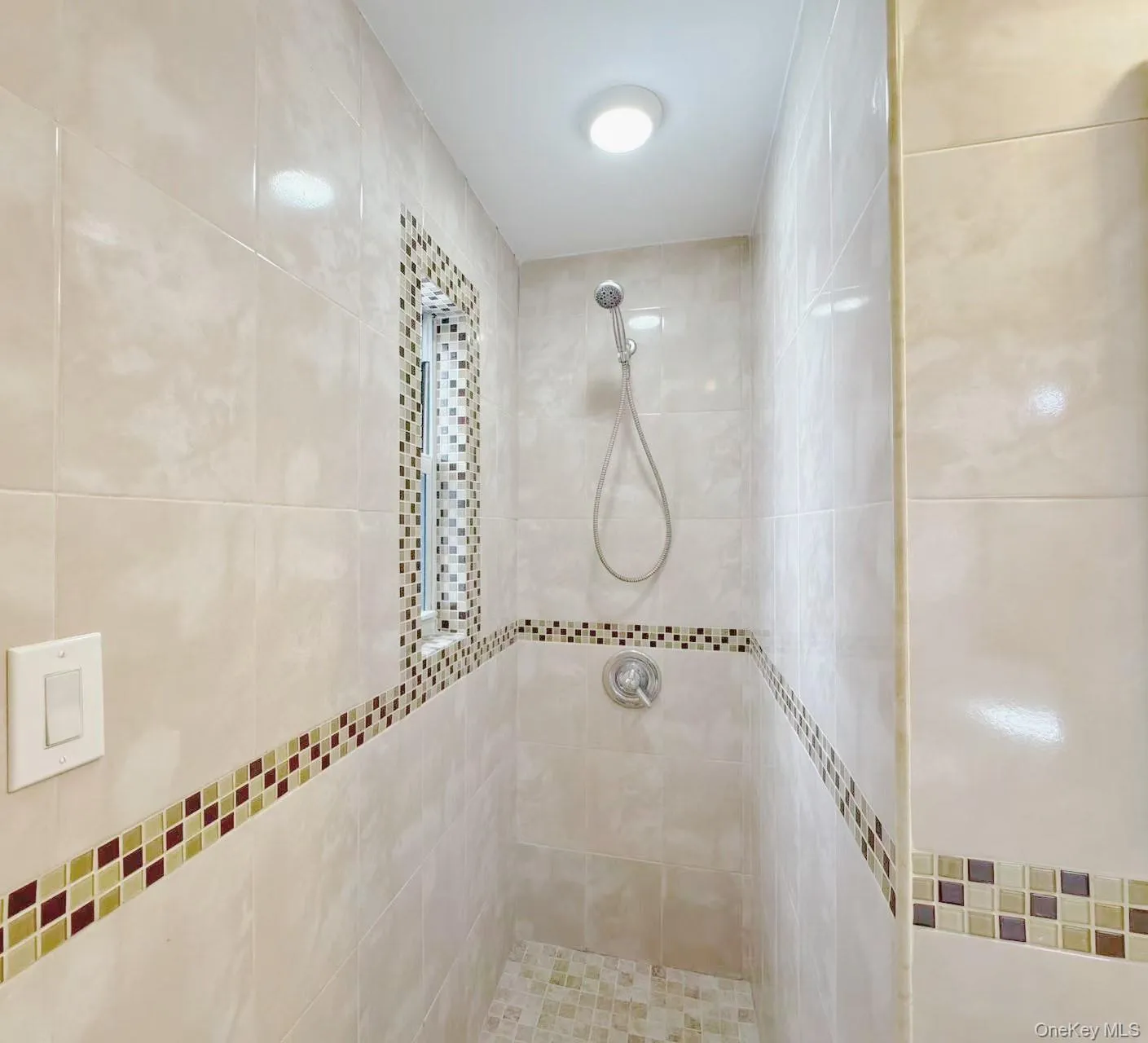 Tiled shower stall featuring mosaic accent bands Tiled shower stall featuring mosaic accent bands
