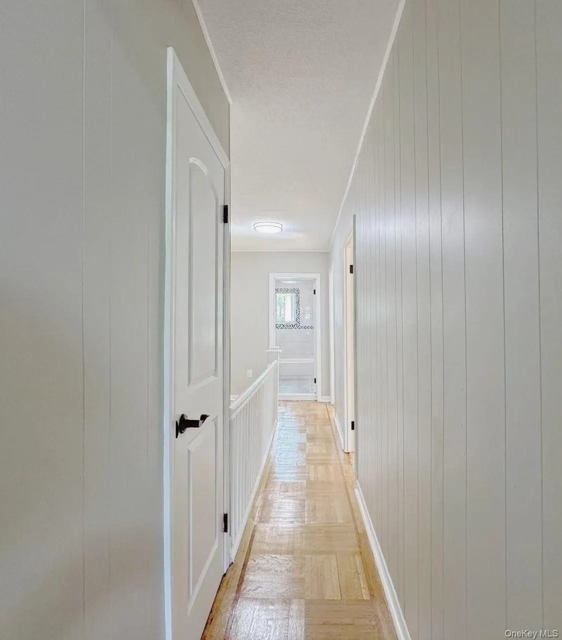 Hallway featuring wood-finish flooring, white paneled walls, and recessed lighting Hallway featuring wood-finish flooring, white paneled walls, and recessed lighting