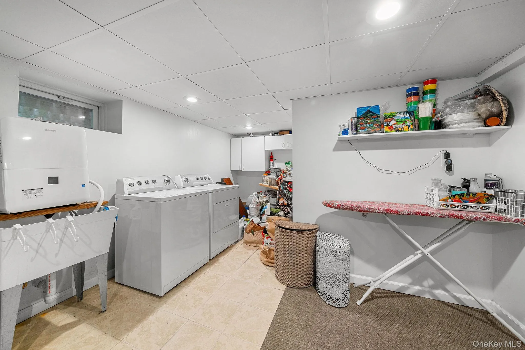 Dedicated laundry area featuring a utility sink, a wall-mounted shelf, recessed lighting, and tile flooring Dedicated laundry area featuring a utility sink, a wall-mounted shelf, recessed lighting, and tile flooring