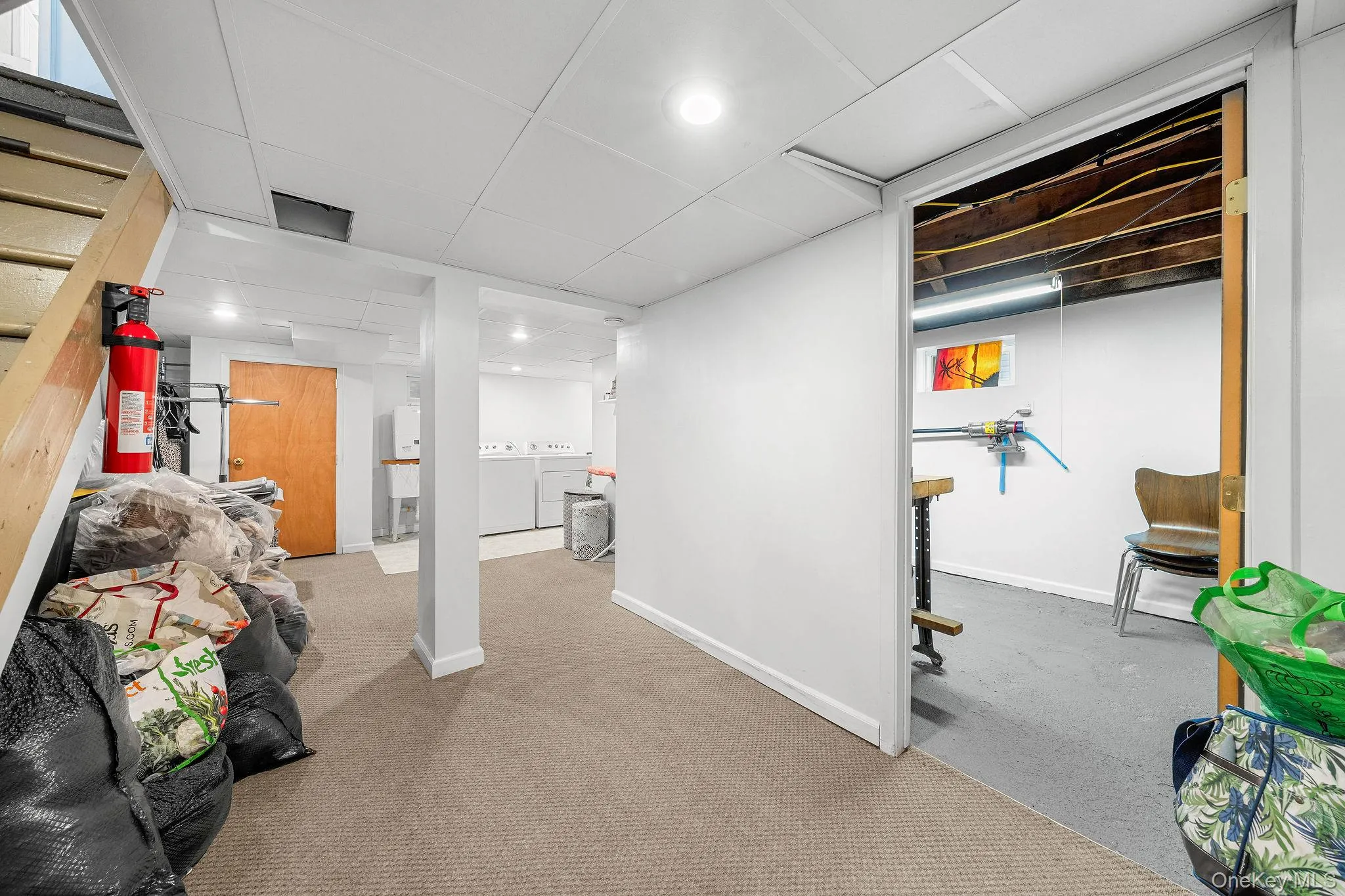 Finished lower level with neutral carpeting, recessed lighting, white paneling, and an open doorway revealing an additional utility area Finished lower level with neutral carpeting, recessed lighting, white paneling, and an open doorway revealing an additional utility area