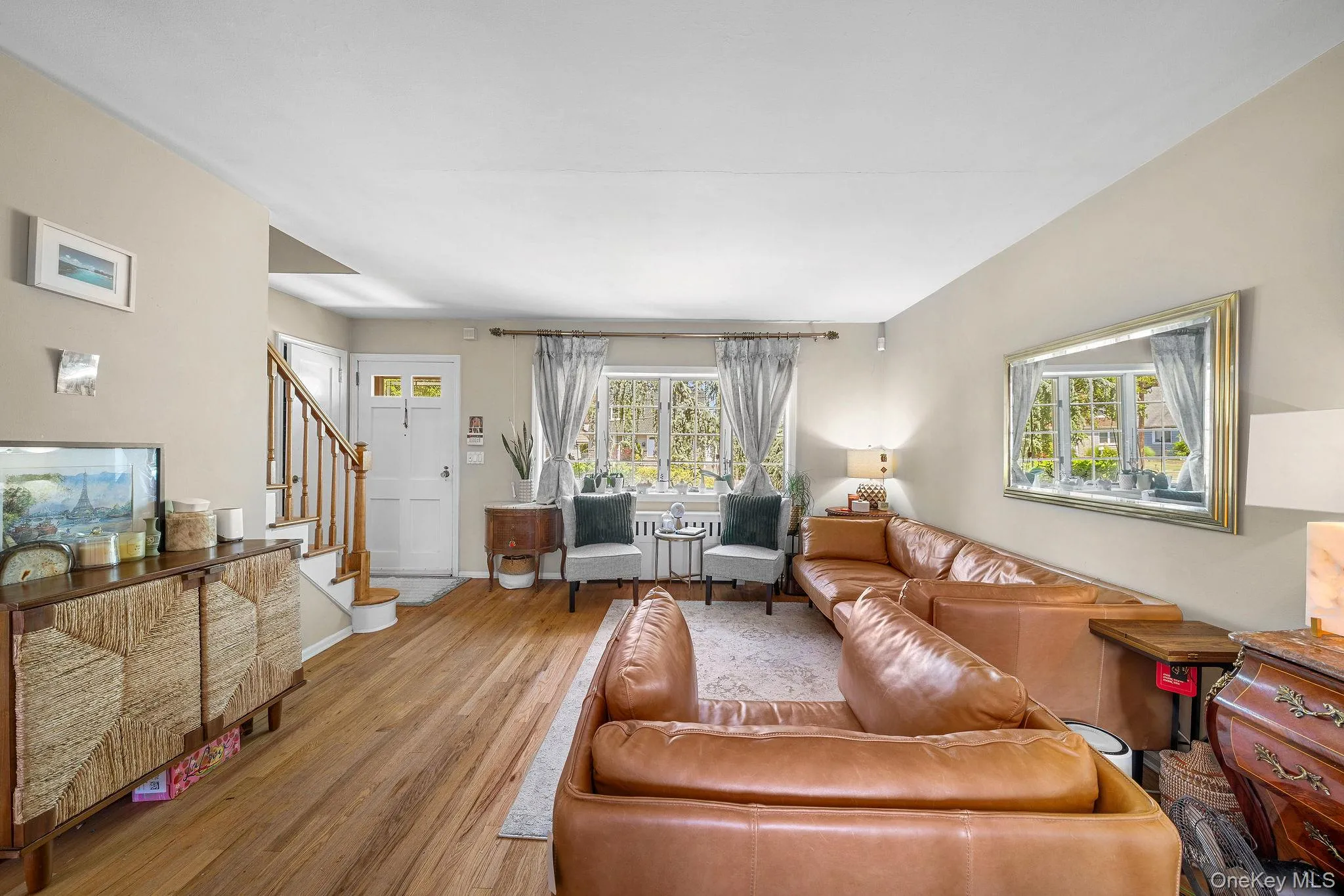 Hardwood flooring extends throughout this interior space, featuring a white paneled entry door with decorative glass inserts Hardwood flooring extends throughout this interior space, featuring a white paneled entry door with decorative glass inserts