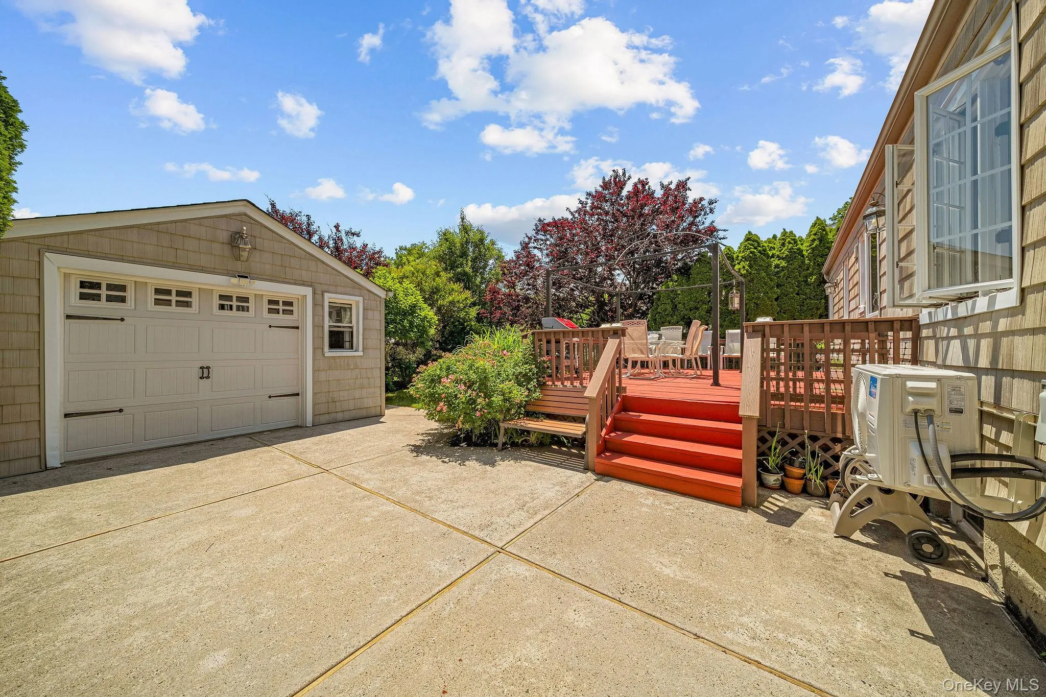 Expansive concrete driveway and detached garage with shaker-style siding Expansive concrete driveway and detached garage with shaker-style siding