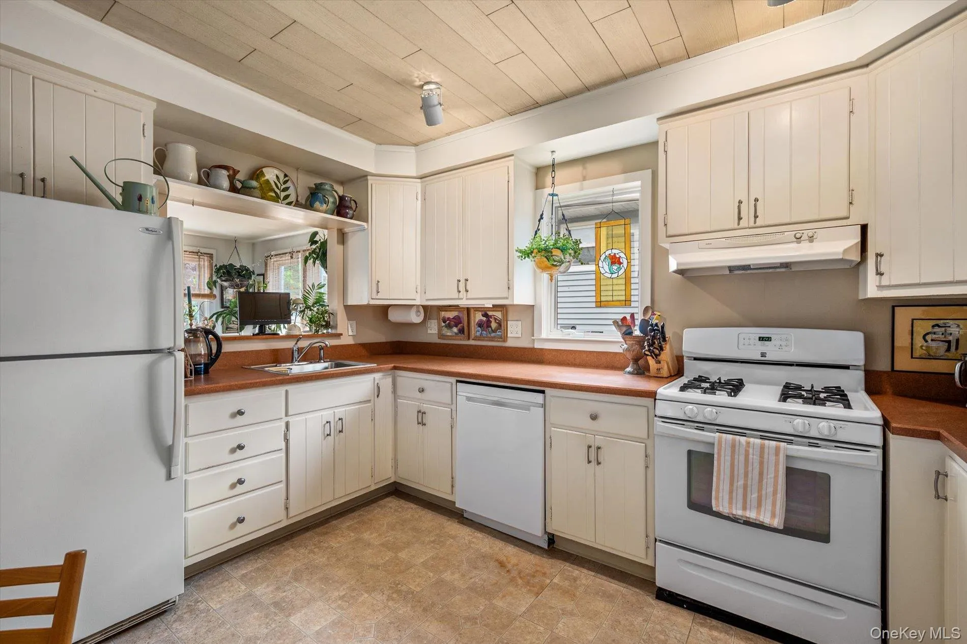 L-shaped kitchen with white cabinetry, brown countertops, and a paneled ceiling L-shaped kitchen with white cabinetry, brown countertops, and a paneled ceiling
