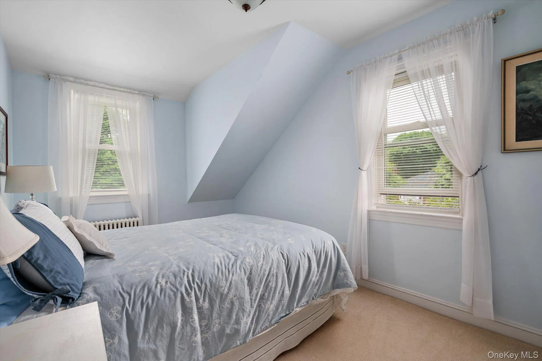 Bedroom featuring two double-hung windows, wall-to-wall carpeting, and sloped ceiling detail Bedroom featuring two double-hung windows, wall-to-wall carpeting, and sloped ceiling detail