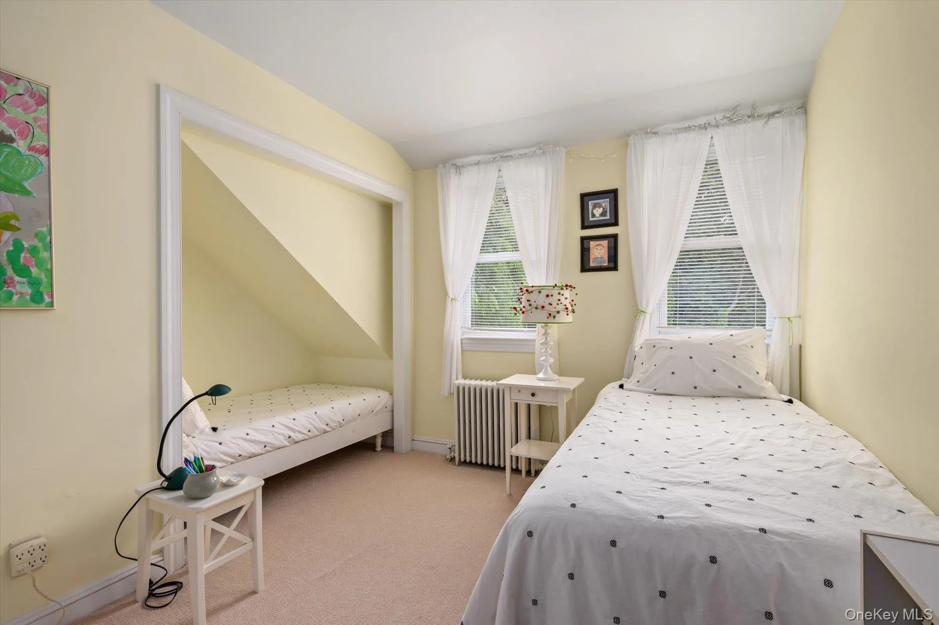 Windowed room with light-colored carpeting, featuring two distinct sleeping areas Windowed room with light-colored carpeting, featuring two distinct sleeping areas
