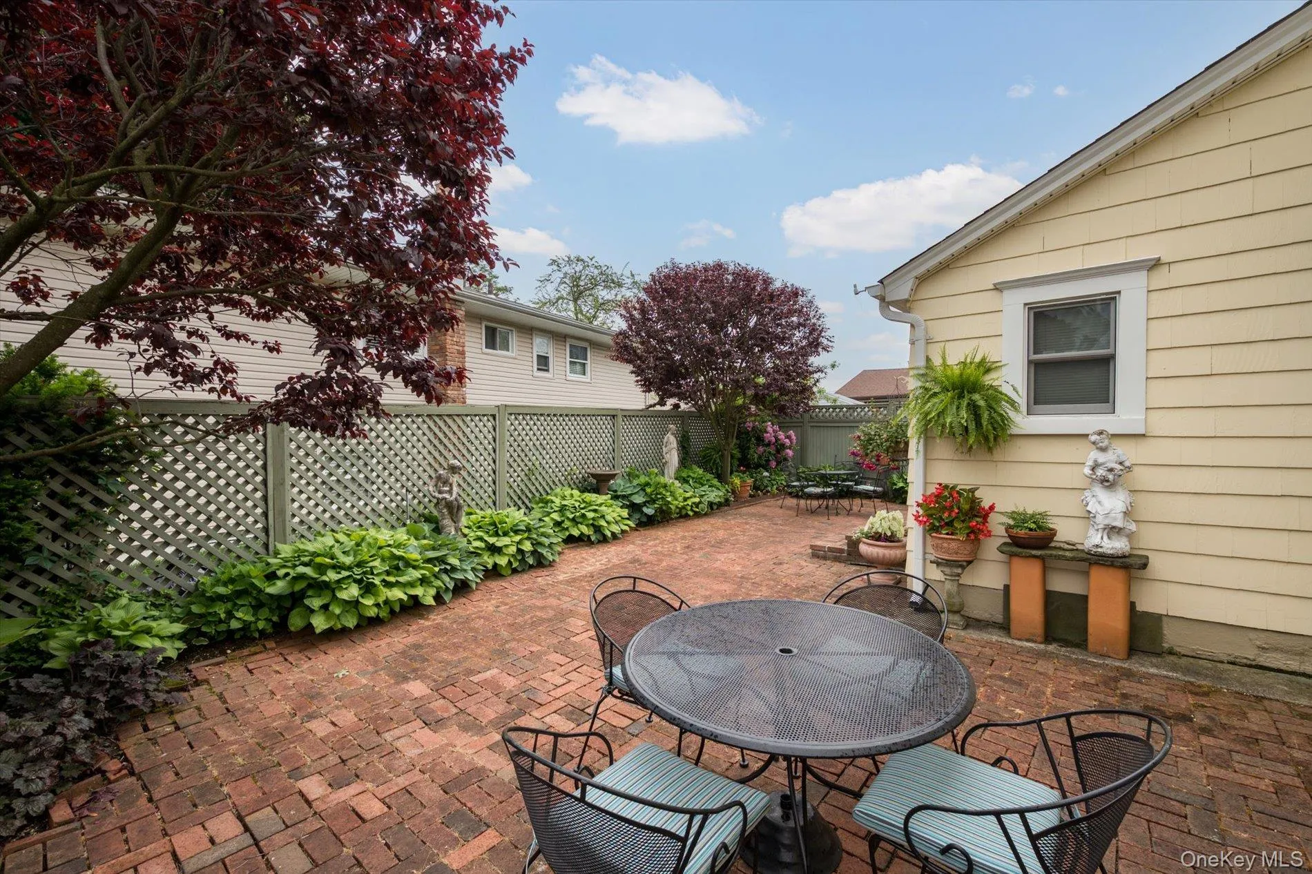 Brick paver patio featuring a lattice privacy fence and mature trees Brick paver patio featuring a lattice privacy fence and mature trees