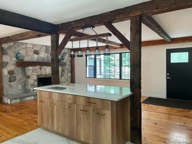 Kitchen featuring beam ceiling, a fireplace, light wood-type flooring, and sink Kitchen featuring beam ceiling, a fireplace, light wood-type flooring, and sink