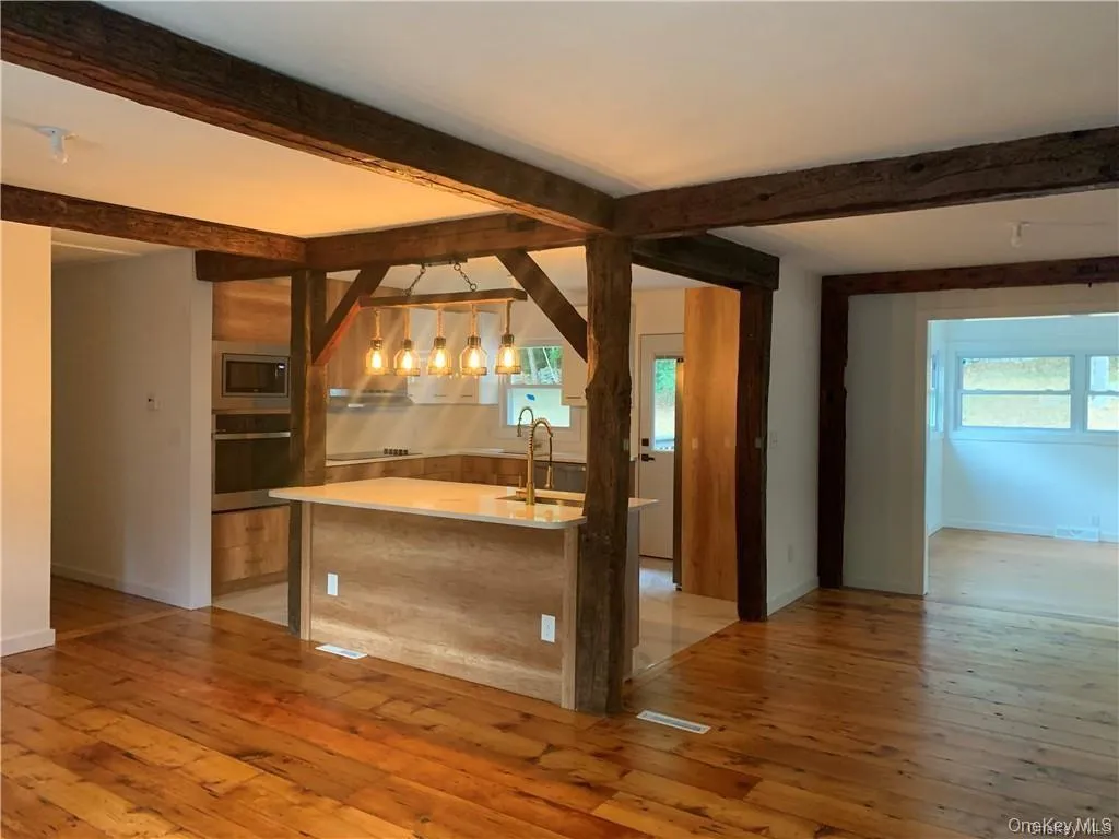 Kitchen featuring an island with sink, pendant lighting, light hardwood / wood-style flooring, and stainless steel appliances Kitchen featuring an island with sink, pendant lighting, light hardwood / wood-style flooring, and stainless steel appliances