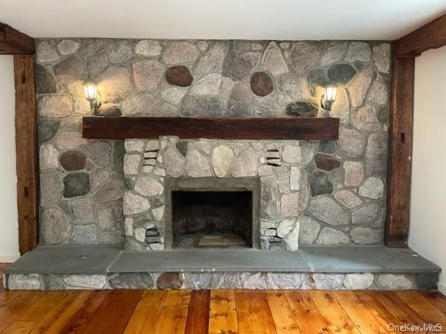 Room details with a stone fireplace and wood-type flooring Room details with a stone fireplace and wood-type flooring