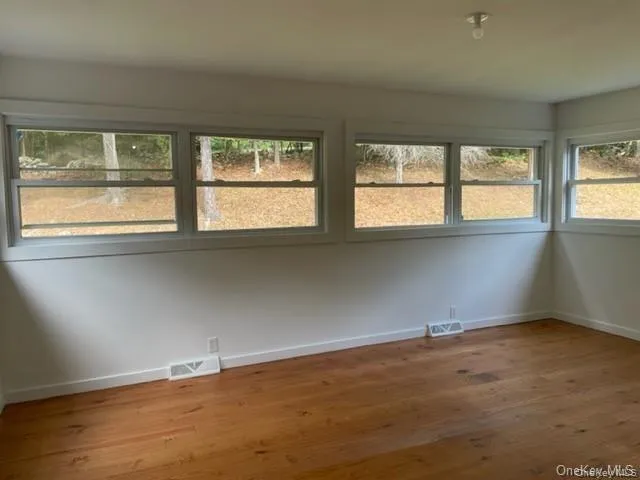 Spare room featuring a wealth of natural light and hardwood / wood-style floors Spare room featuring a wealth of natural light and hardwood / wood-style floors