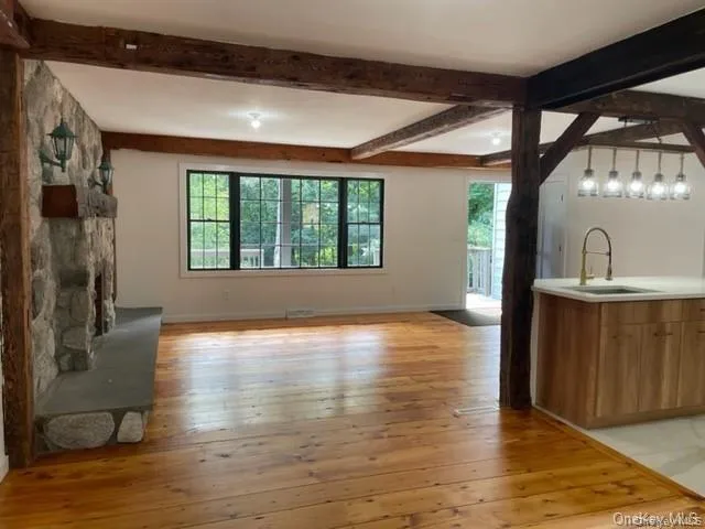Unfurnished living room with beamed ceiling, sink, and light wood-type flooring Unfurnished living room with beamed ceiling, sink, and light wood-type flooring