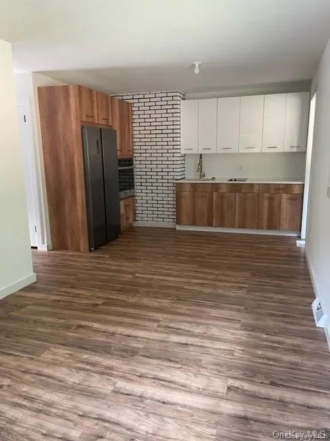 Unfurnished living room with brick wall and wood-type flooring Unfurnished living room with brick wall and wood-type flooring