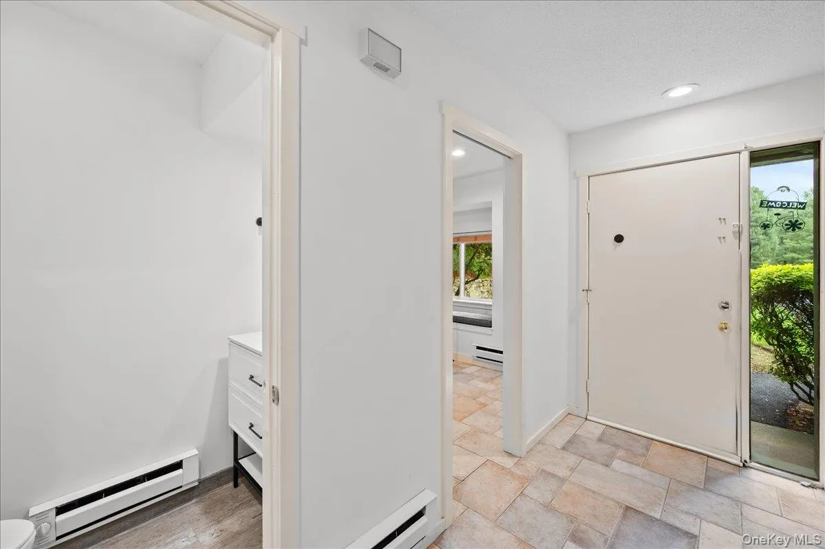 Foyer entrance with baseboard heating, plenty of natural light, light stone finish flooring, and recessed lighting Foyer entrance with baseboard heating, plenty of natural light, light stone finish flooring, and recessed lighting