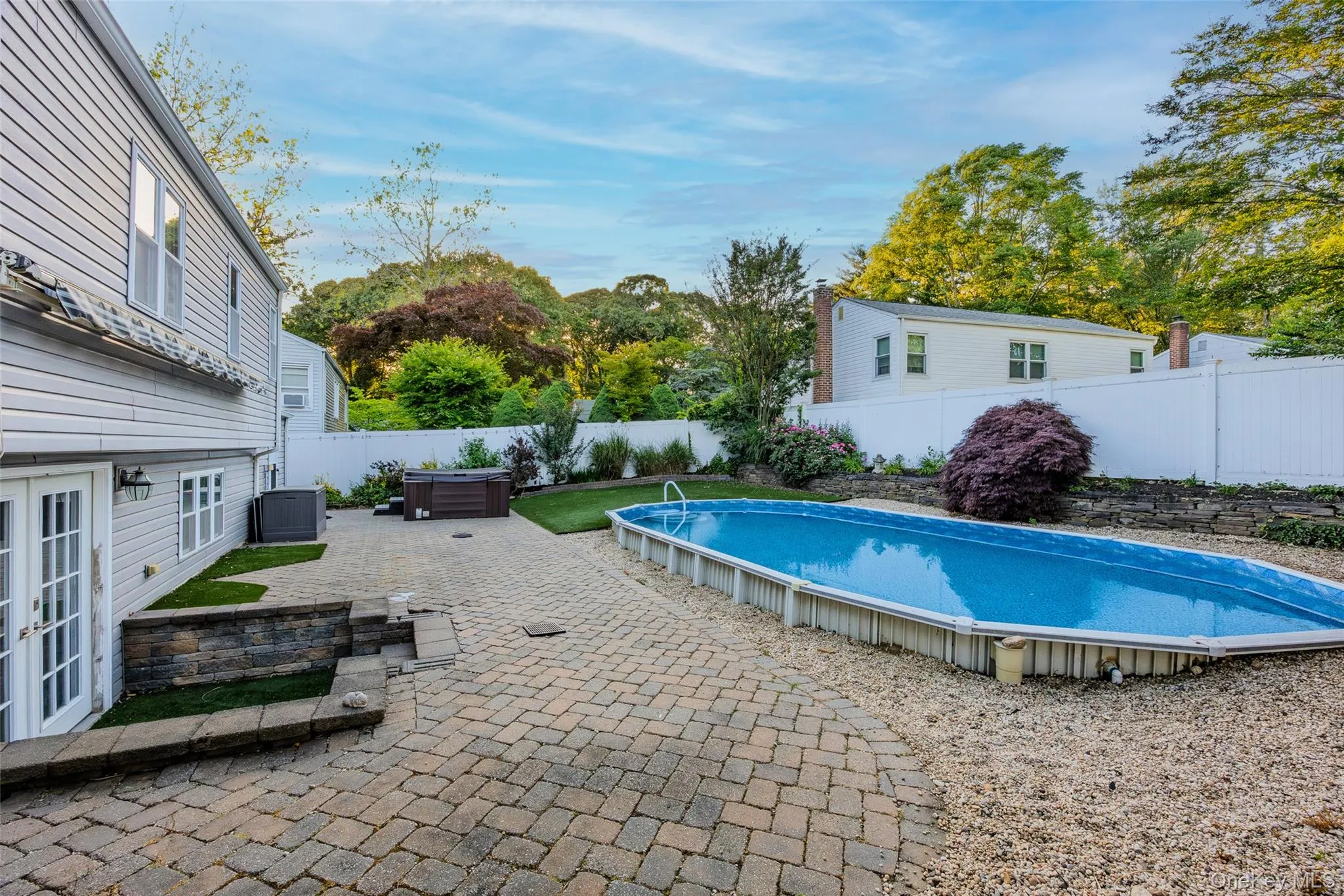 Outdoor space featuring a paved patio, above-ground pool, and hot tub Outdoor space featuring a paved patio, above-ground pool, and hot tub