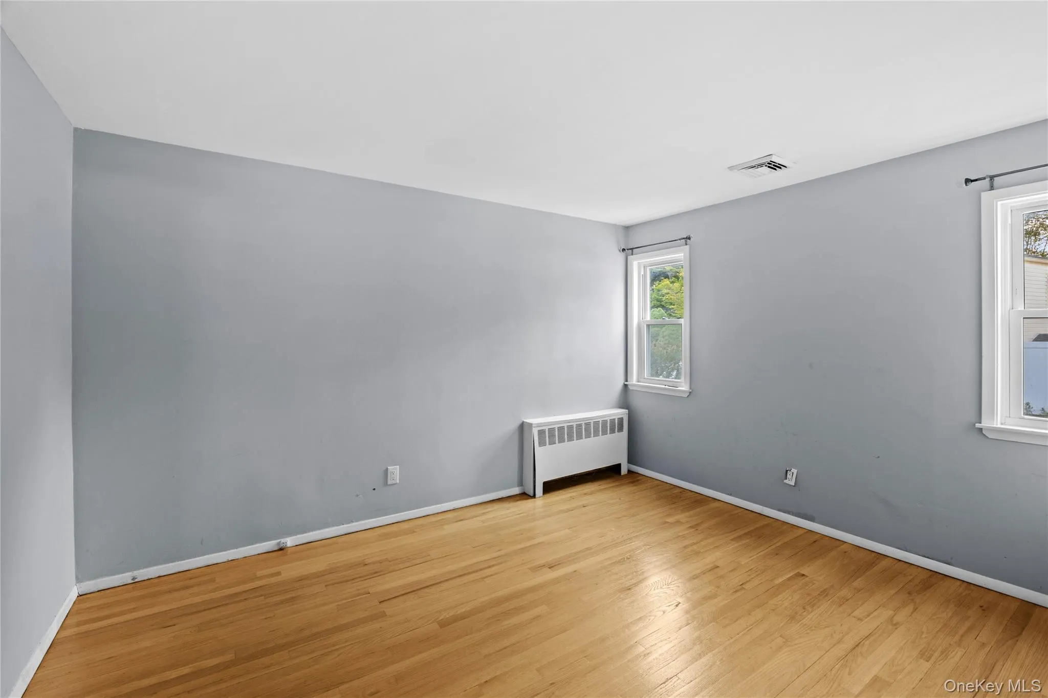 Hardwood flooring, light gray wall finishes, white baseboards, and multiple windows with white trim Hardwood flooring, light gray wall finishes, white baseboards, and multiple windows with white trim