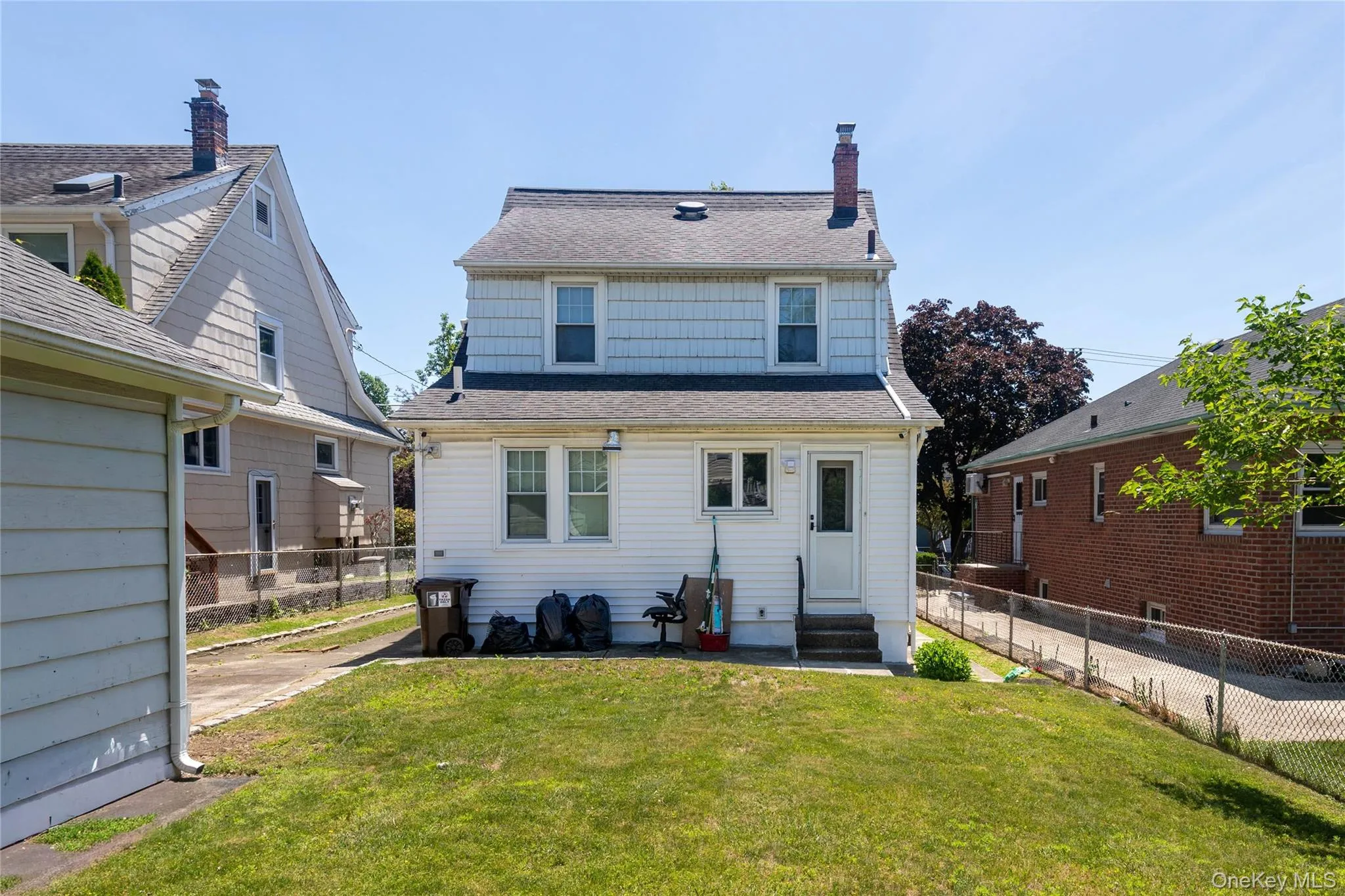 Rear exterior of a two-story residence featuring white siding on the first level and light blue shingle siding on the second story Rear exterior of a two-story residence featuring white siding on the first level and light blue shingle siding on the second story