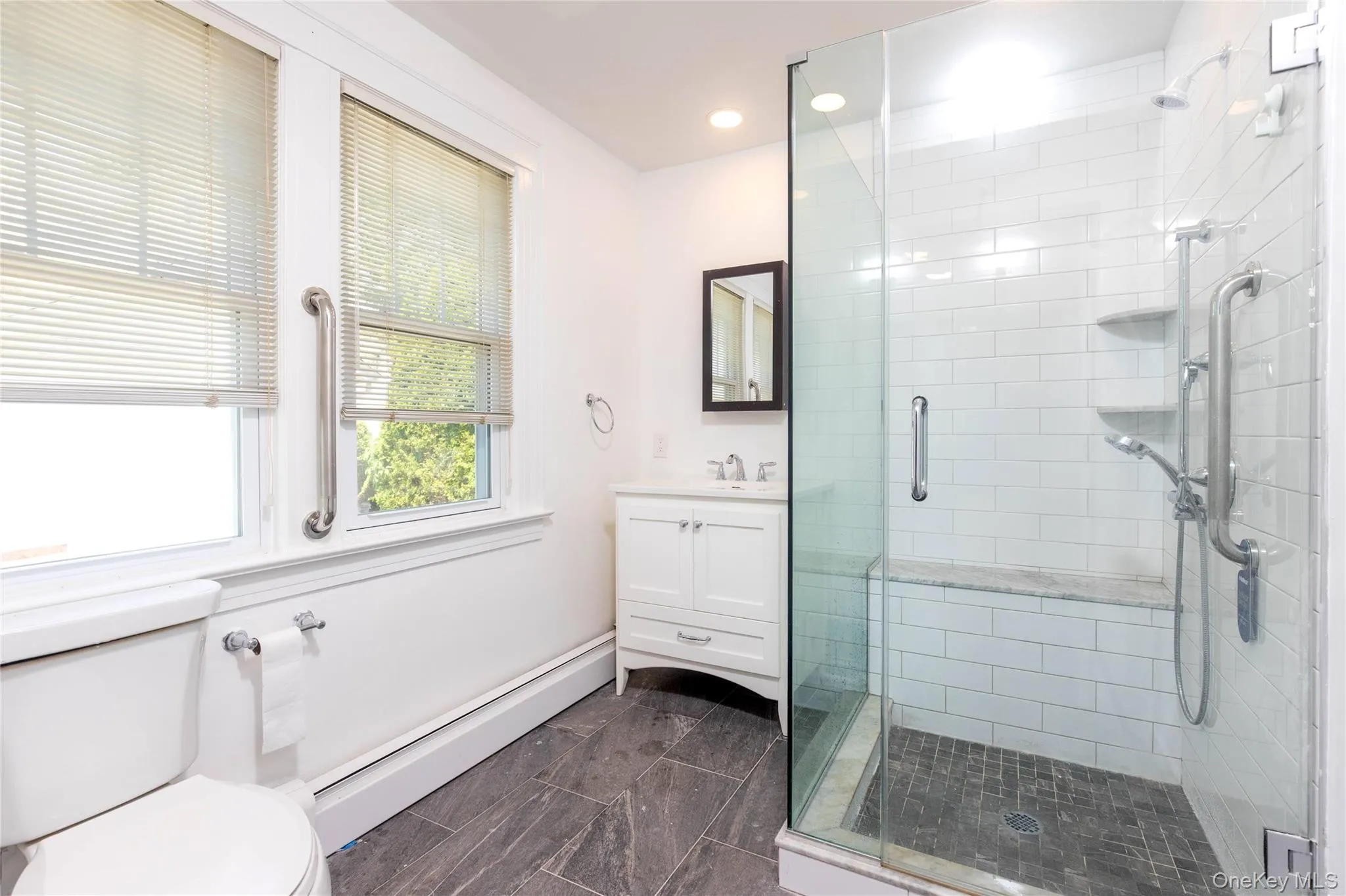 Glass-enclosed shower with white subway tile, a built-in bench, and dual shower heads Glass-enclosed shower with white subway tile, a built-in bench, and dual shower heads