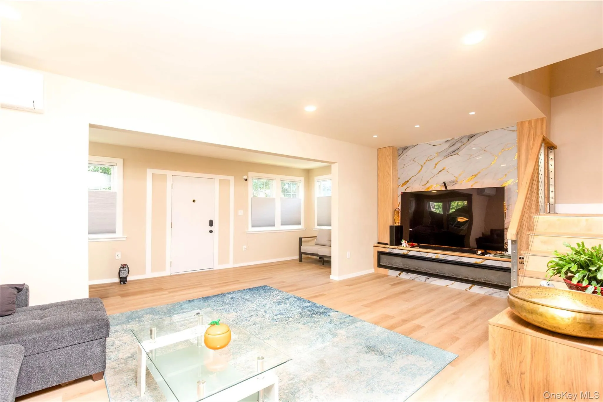 Open-concept living space featuring wood-finish flooring, recessed lighting, and a modern accent wall with a large built-in media console Open-concept living space featuring wood-finish flooring, recessed lighting, and a modern accent wall with a large built-in media console