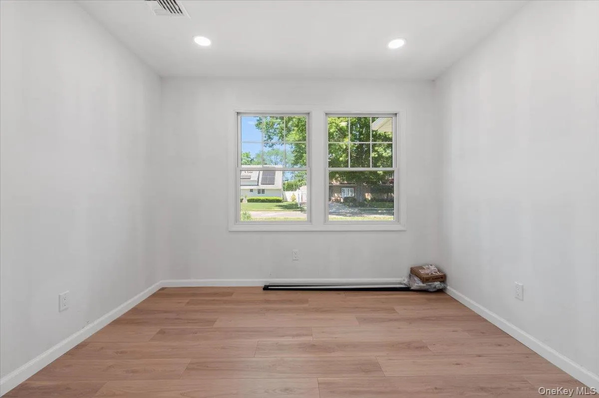 Room featuring wood-finish flooring, recessed lighting, and white walls Room featuring wood-finish flooring, recessed lighting, and white walls