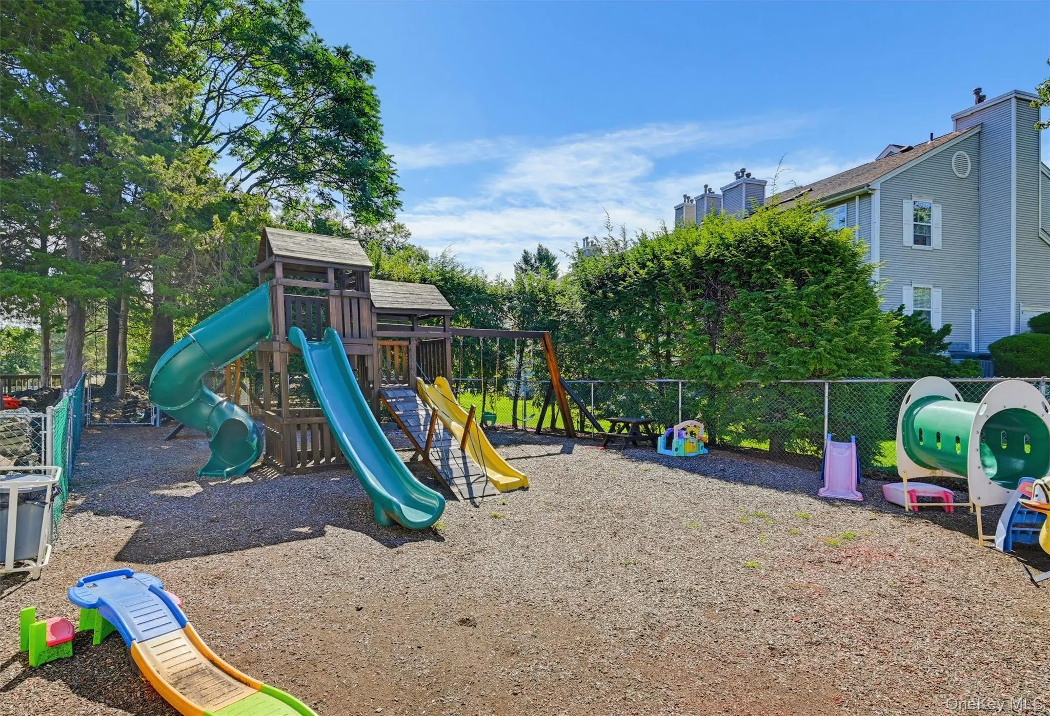 Community playground with slides, swings, and fenced play area. Community playground with slides, swings, and fenced play area.
