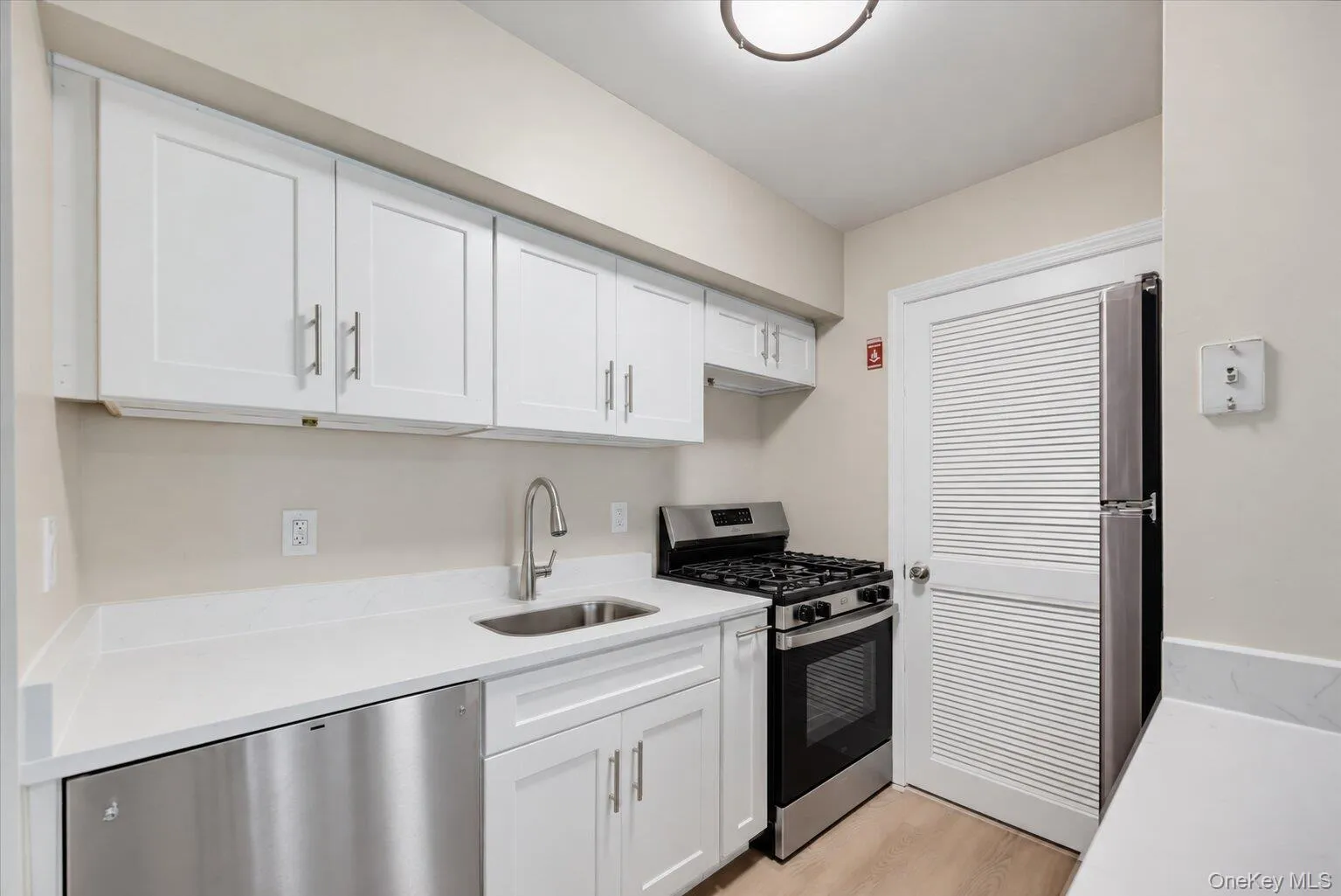 Close-up view of the kitchen featuring white cabinetry, stainless steel dishwasher and gas range, and ample counter space Close-up view of the kitchen featuring white cabinetry, stainless steel dishwasher and gas range, and ample counter space