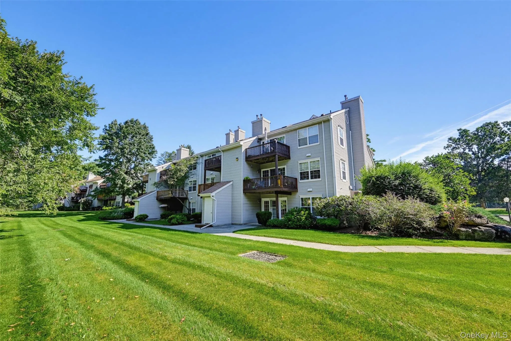 Expansive exterior view of the building surrounded by well-maintained green space and landscaping. Expansive exterior view of the building surrounded by well-maintained green space and landscaping.