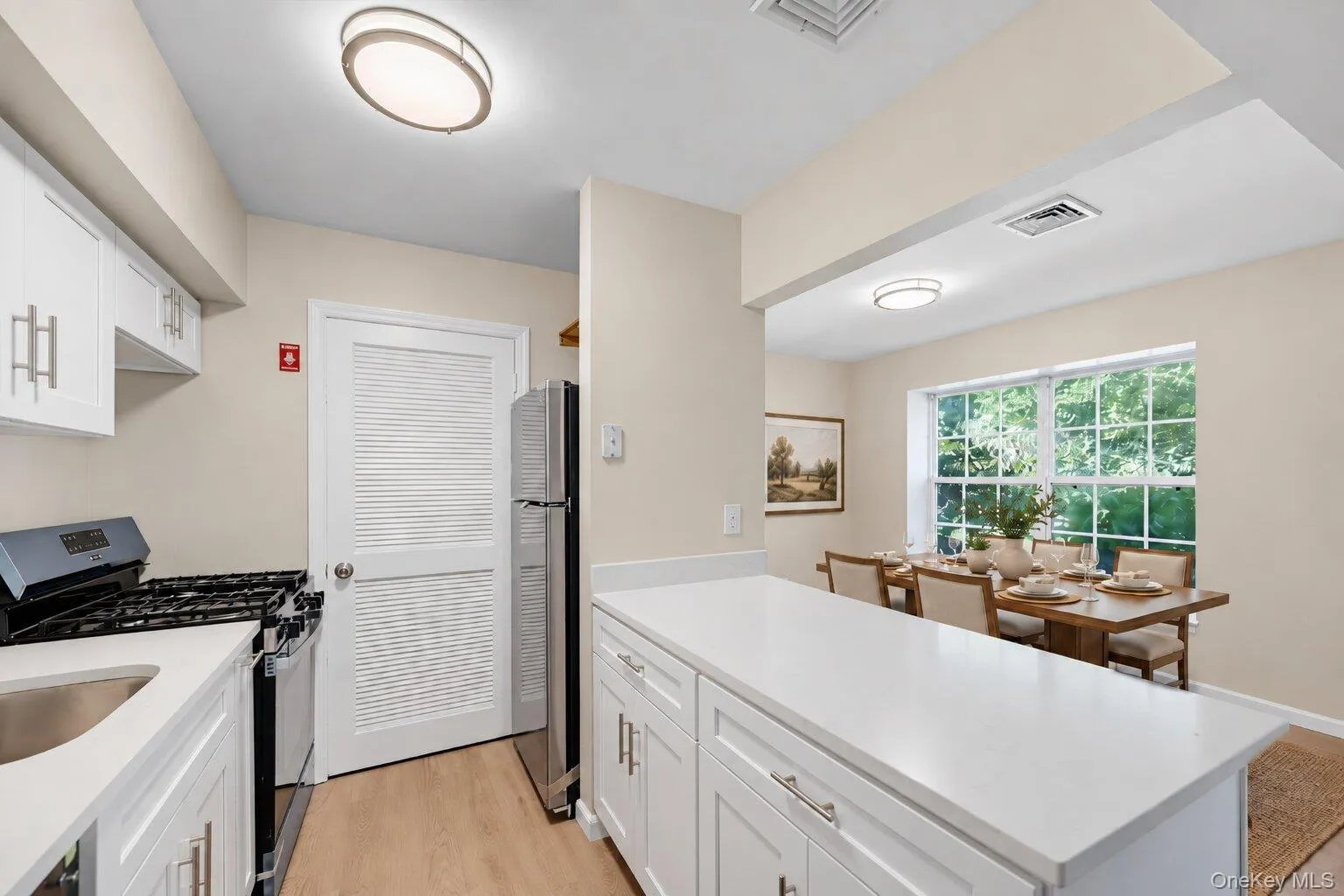 Virtually Staged Dining area. Updated kitchen with white cabinetry, quartz-style countertops, stainless steel appliances, breakfast bar, and adjoining dining area. Virtually Staged Dining area. Updated kitchen with white cabinetry, quartz-style countertops, stainless steel appliances, breakfast bar, and adjoining dining area.