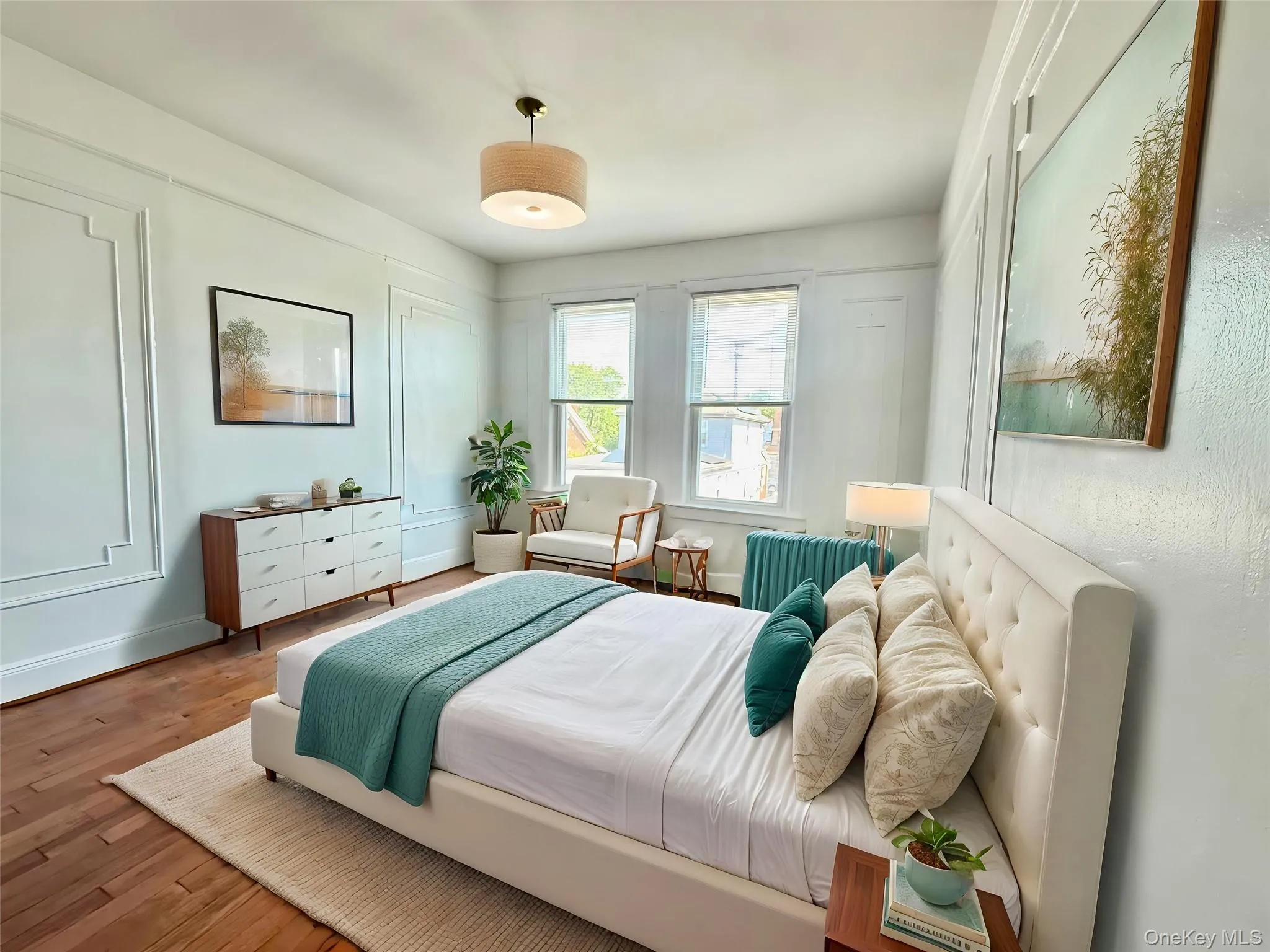 Hardwood flooring in a bright room featuring decorative wall molding, two windows, and a ceiling-mounted light fixture Hardwood flooring in a bright room featuring decorative wall molding, two windows, and a ceiling-mounted light fixture